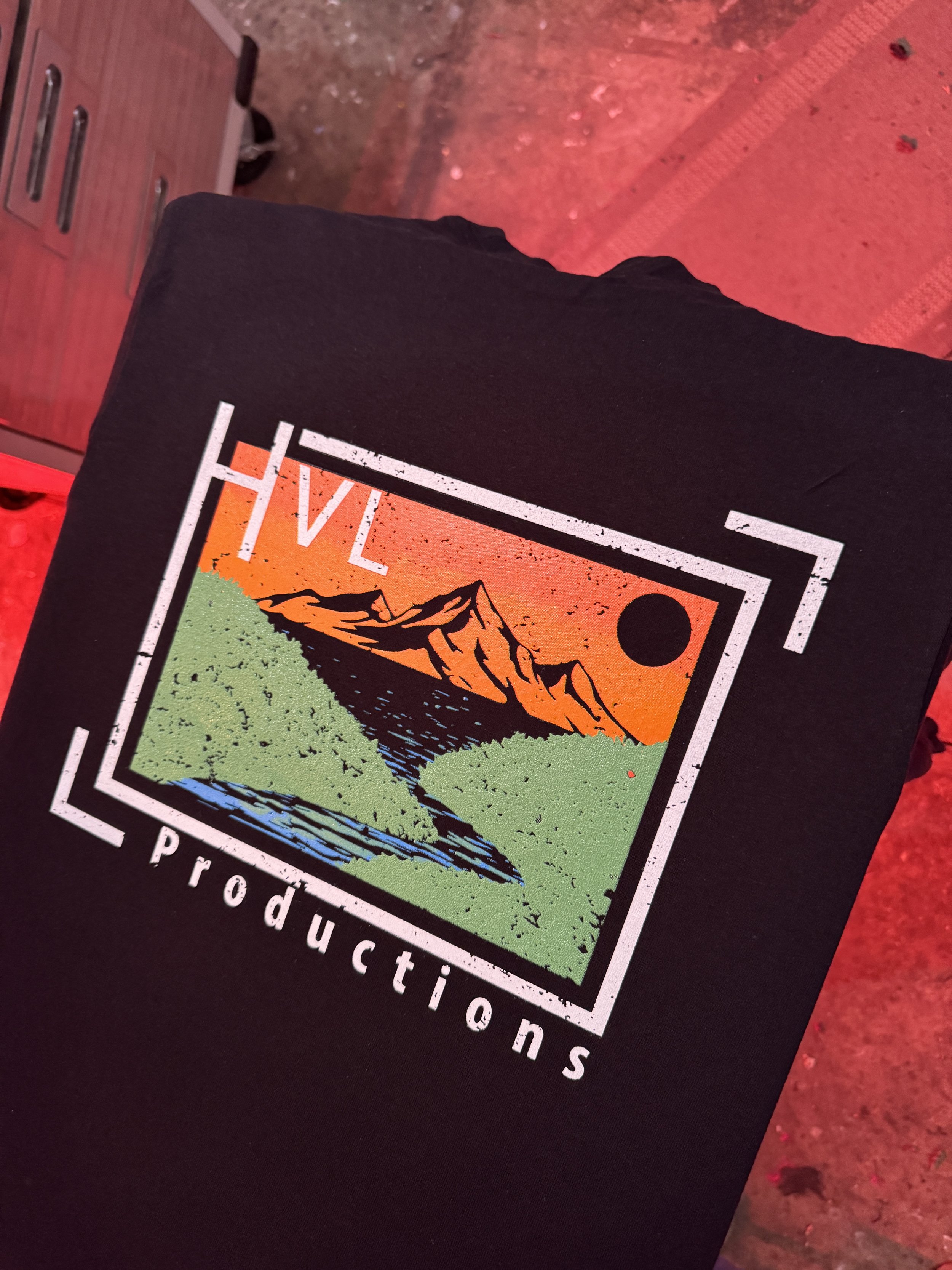 Black T-shirt with a Mountain and Lake Nature Logo design and text 'HVL Productions'