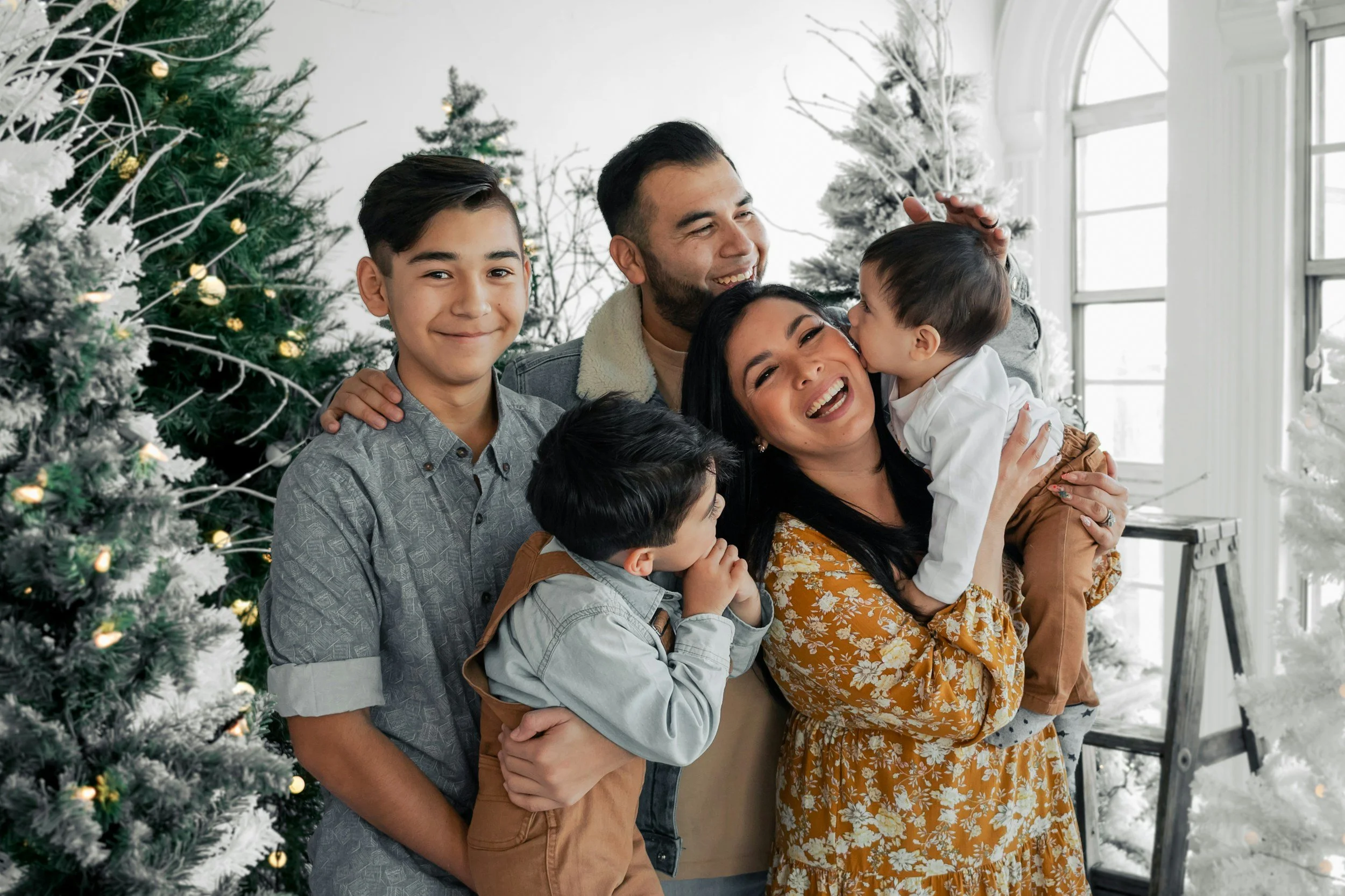 A family smiling around Christmas trees