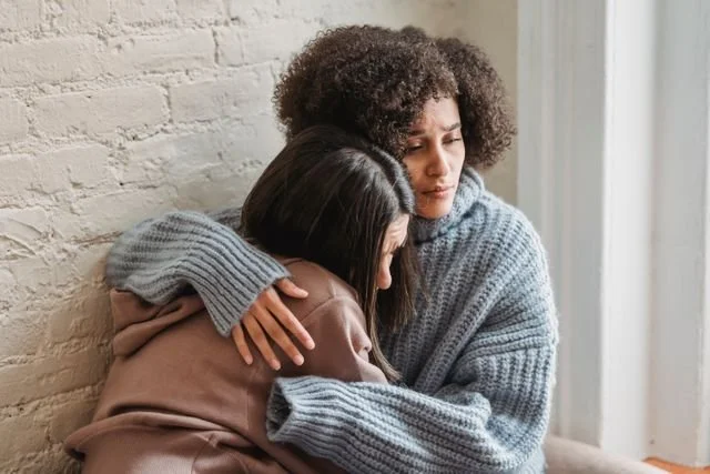 A person being comforted by her friend