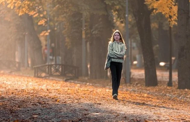 A young woman walking in the park in the fall