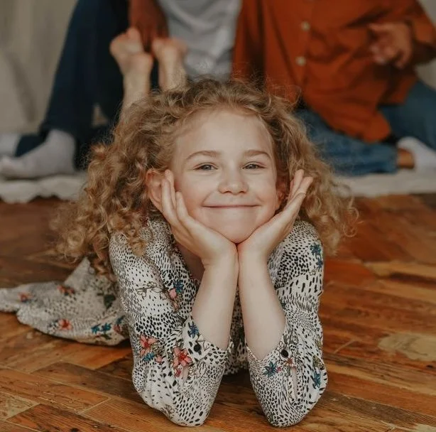 A smiling child with her parents behind her
