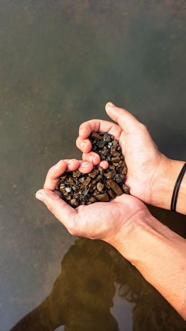 hand holding pebbles in a heart shape