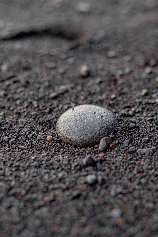 a smooth stone stuck in wet sand