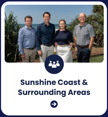 Group of four people standing outdoors near plants with ocean in background, sunny sky.