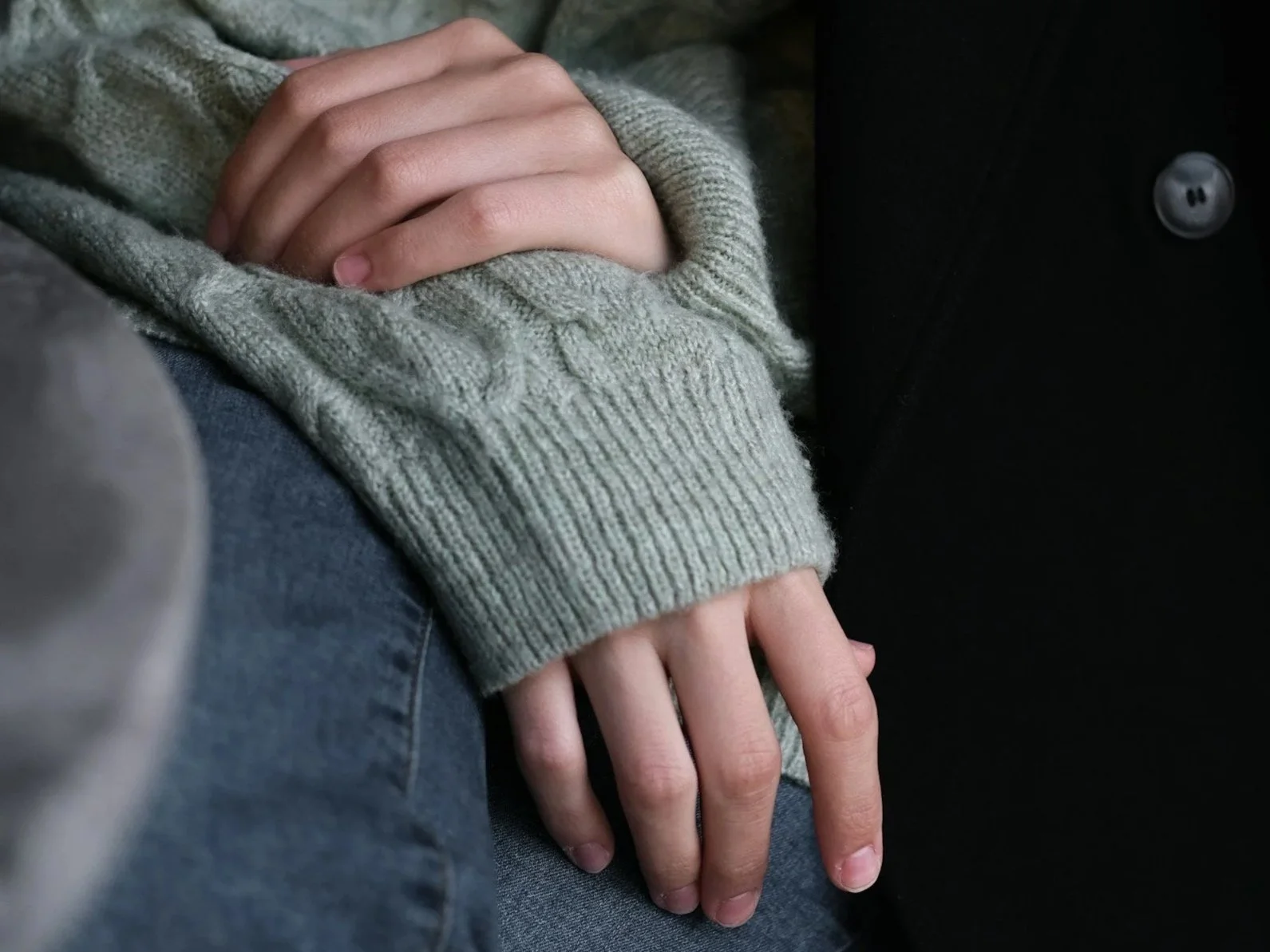 Hands resting in a lap, conveying a quiet moment of reflection