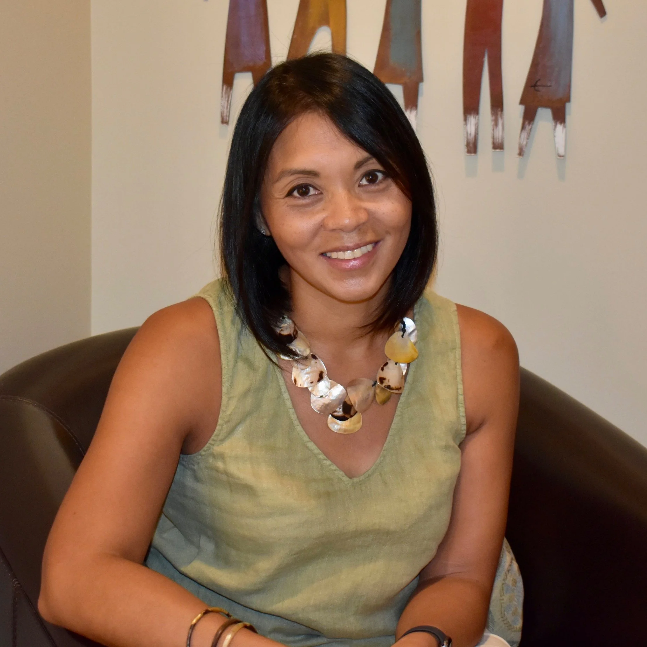 Carminda Passino smiling, wearing a green top and layered necklace