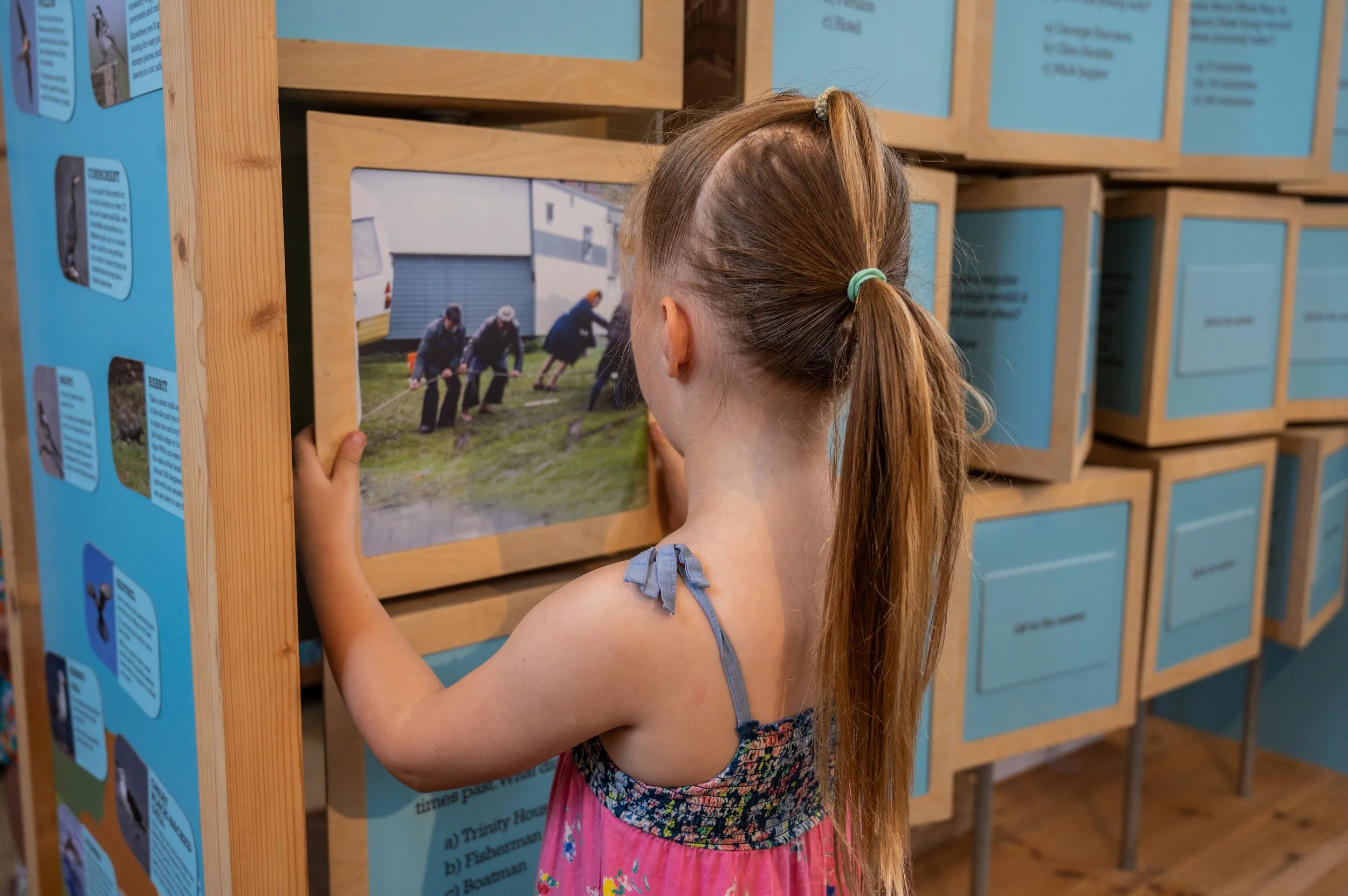 A young girl looking at a photo on a rotating block 