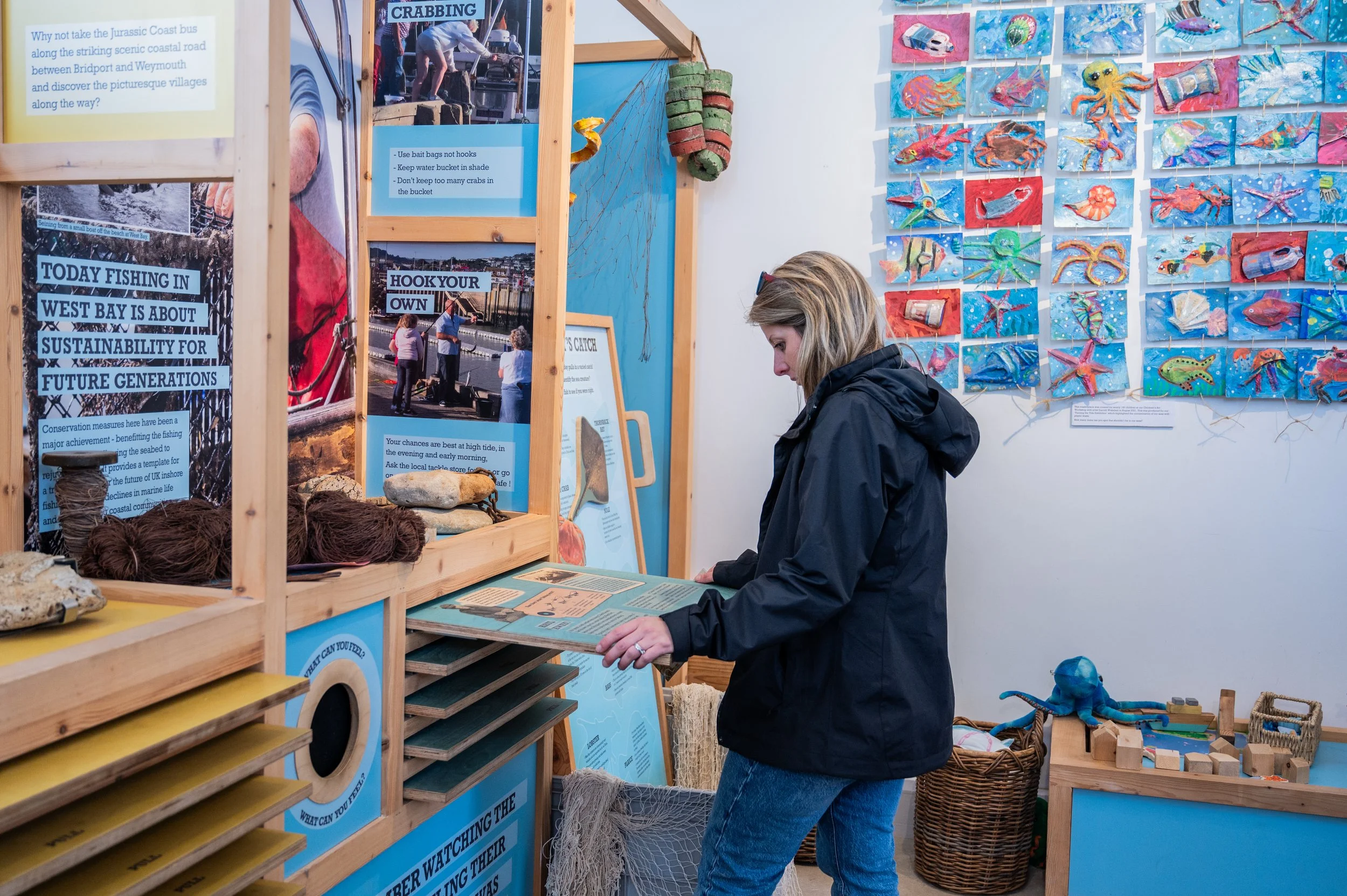 a woman pulling out a wooden board to find out more information about the display 