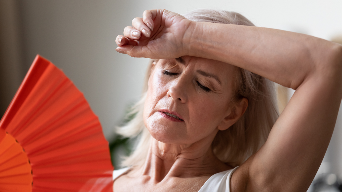 a person with her hand on her forehead while using a fan