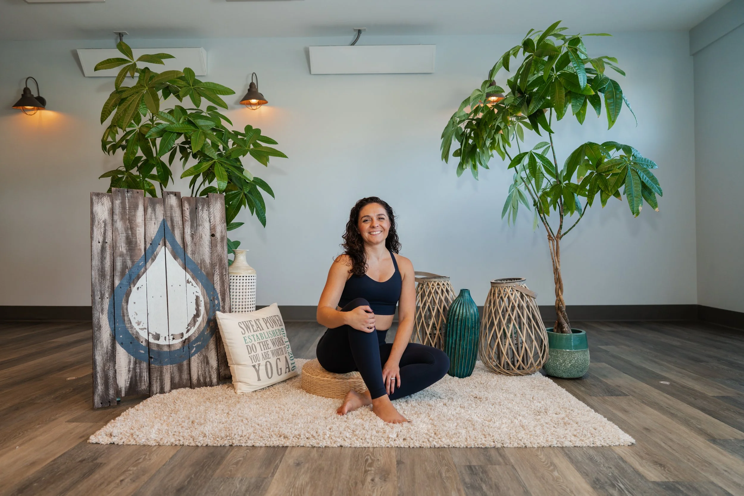 Alli Schubach smiling while sitting indoors next to a potted