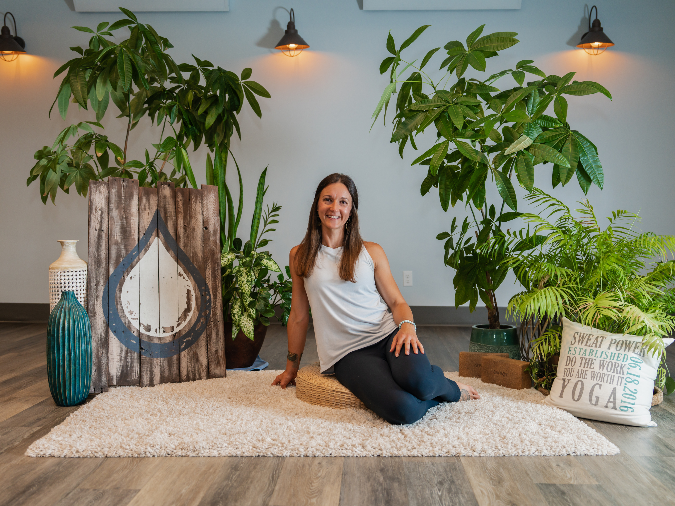 Krystal Say smiling brightly towards the viewer while sitting cross-legged in a chair