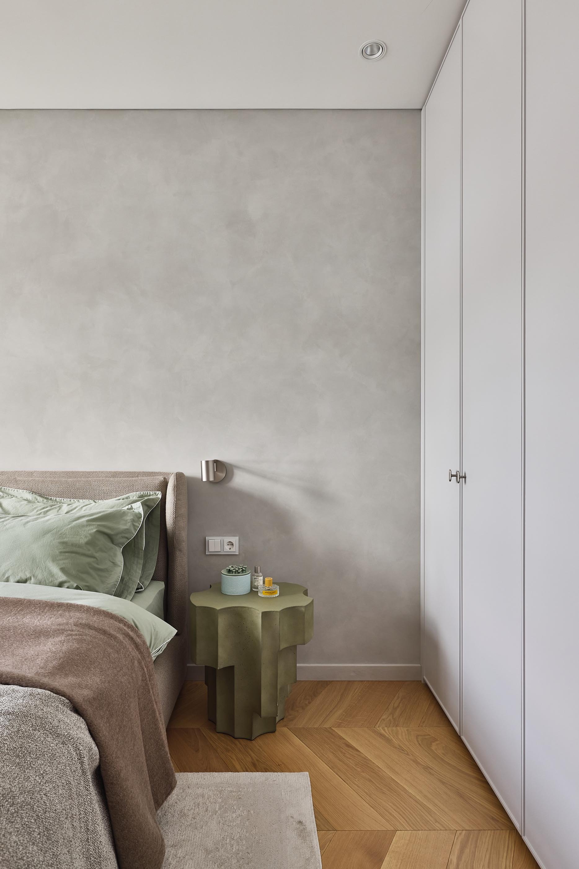Modern bedroom, a contemporary wall-mounted brushed steel lamp, MINOTTI bedding, CC-tapis rug, and a TACCHINI side table. 