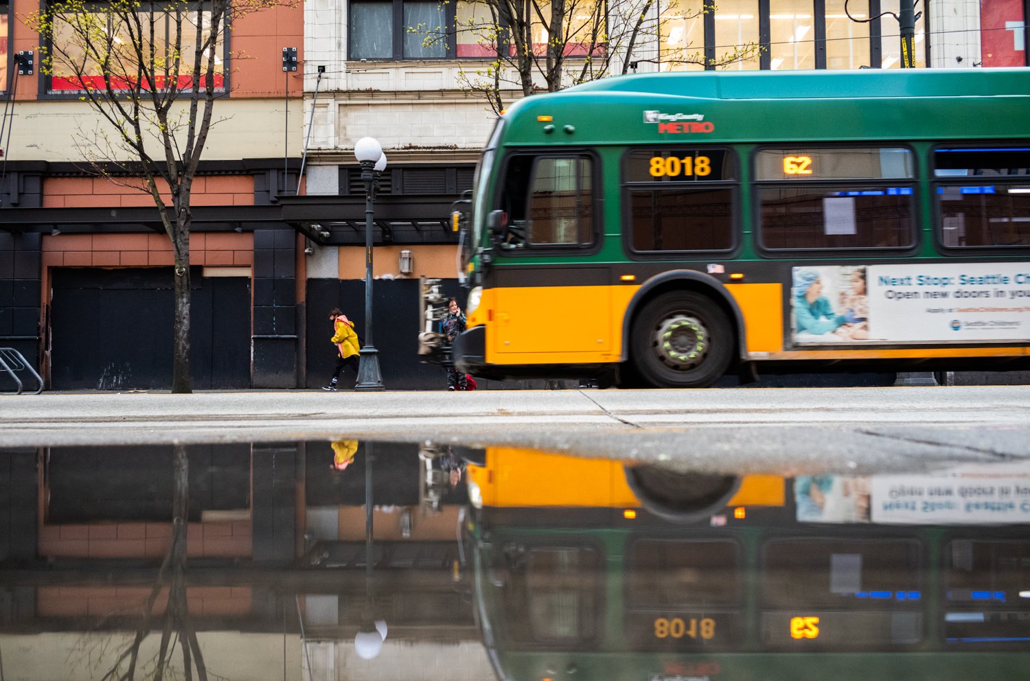 A public bus is reflected in a puddle on 3rd Avenue in Seattle, Washington, USA on April 4, 2022.