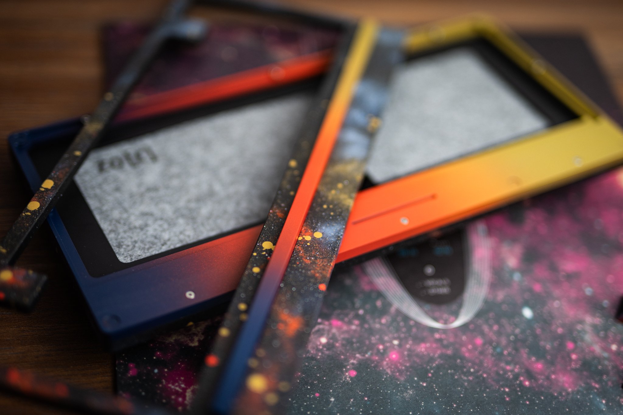 An orange and gray metal frame, possibly part of a keyboard, resting on a black fabric case beside a textured concrete surface.