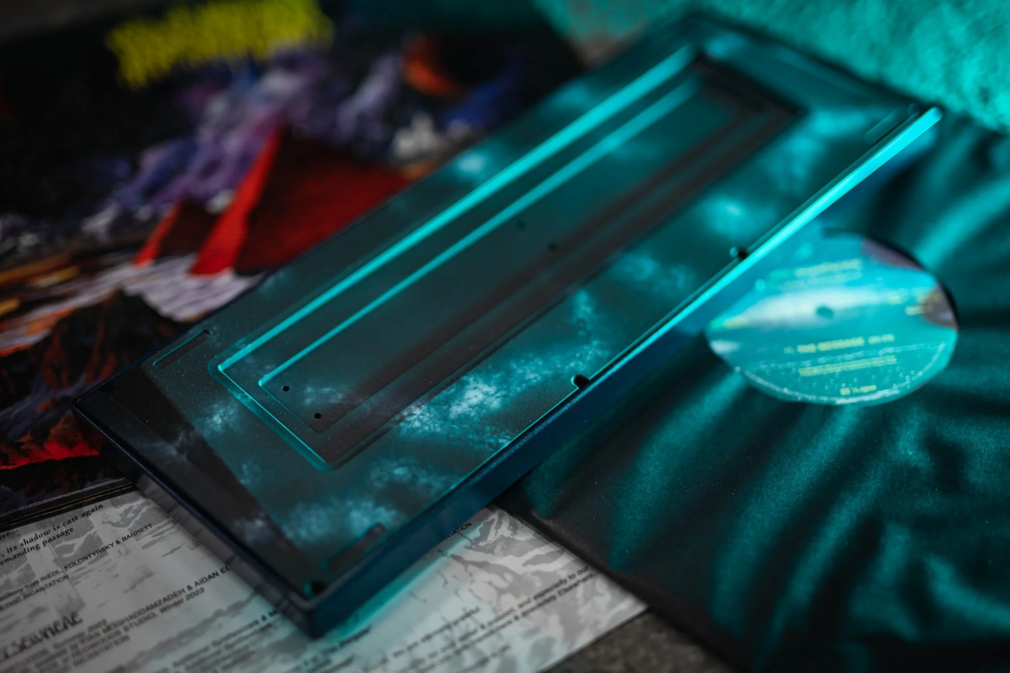 A booklet titled 'Stargate Research Society presents: A meditative inquiry on the Mystery & Nature of human consciousness, as revealed by Blood Incantation,' lying on a surface with illustrations, beneath a galaxy-patterned Monokei device.