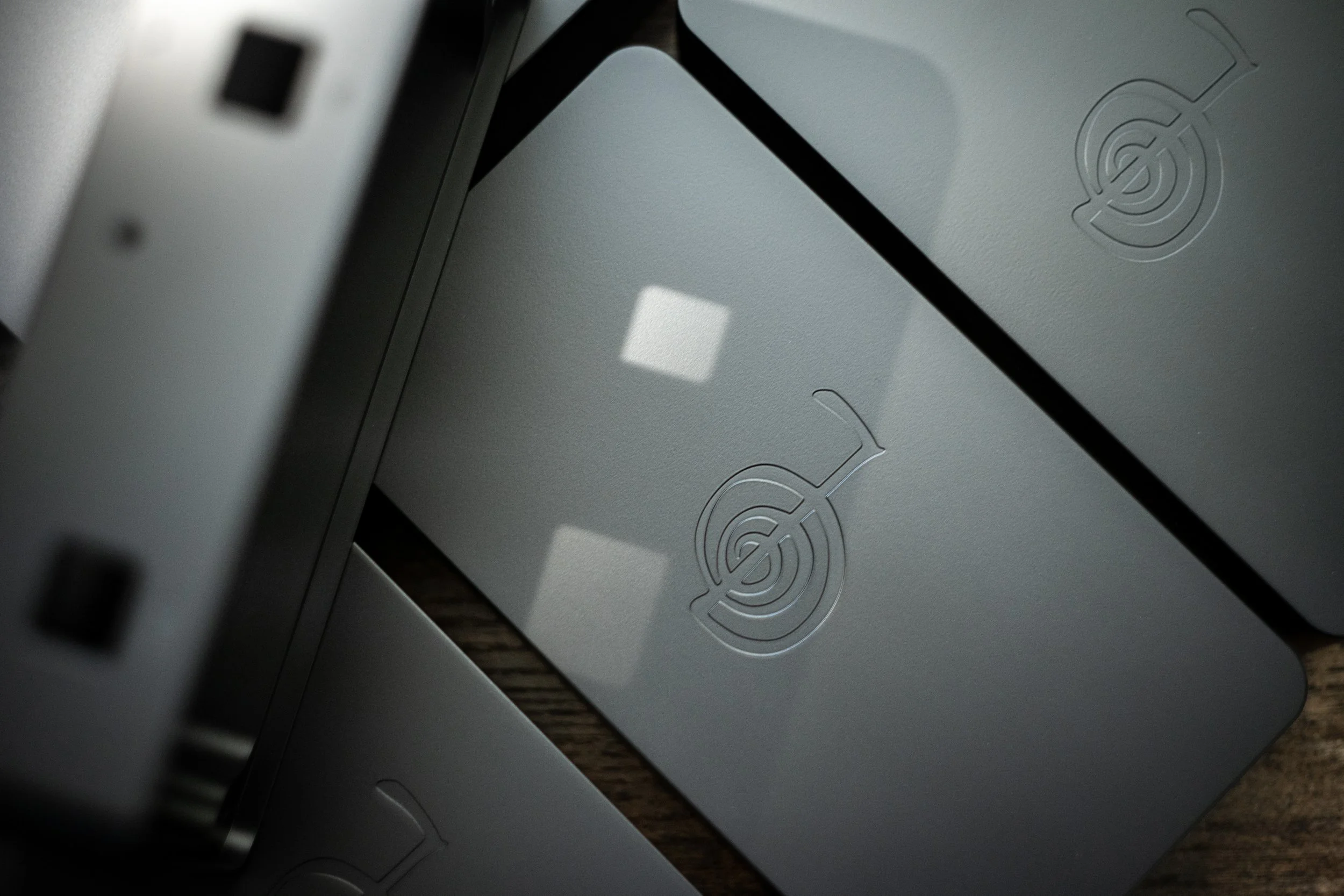 Close-up of a gray electronic device with a logo embossed on its surface, showing part of its edge and some ports.
