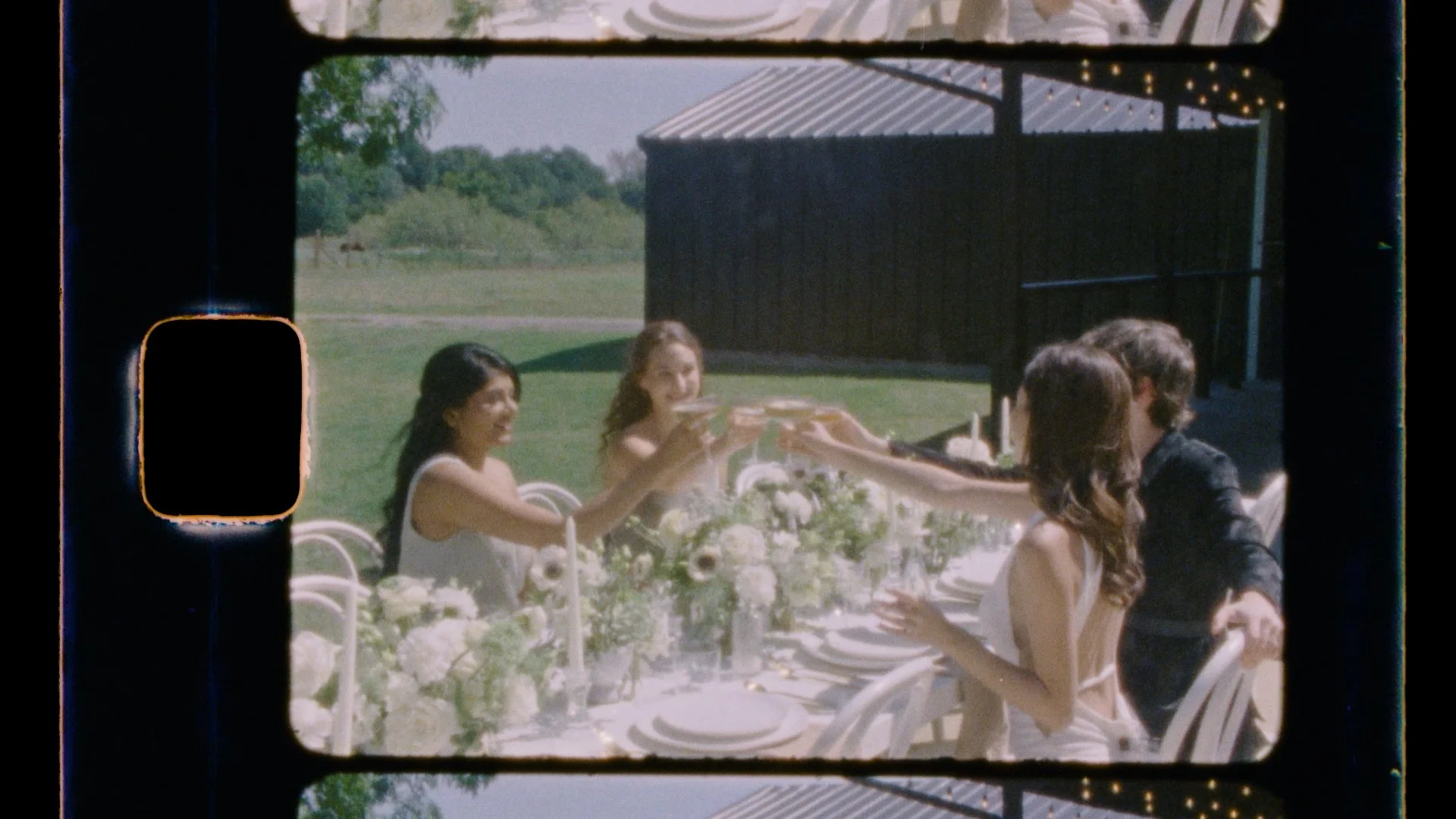 Attendees at an intimate summer wedding toast with the two female newlyweds during their outdoor reception at The Emerson Venue in Kaufman, Texas.