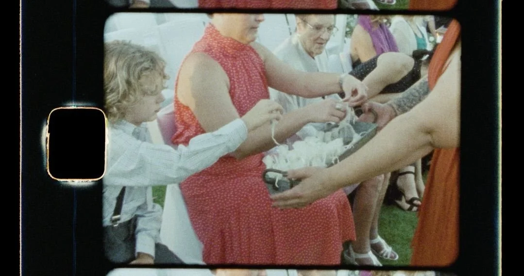 attendees at an outdoor wedding sit in their chairs bfore the ceremony and grab bubble containers out of a basket.