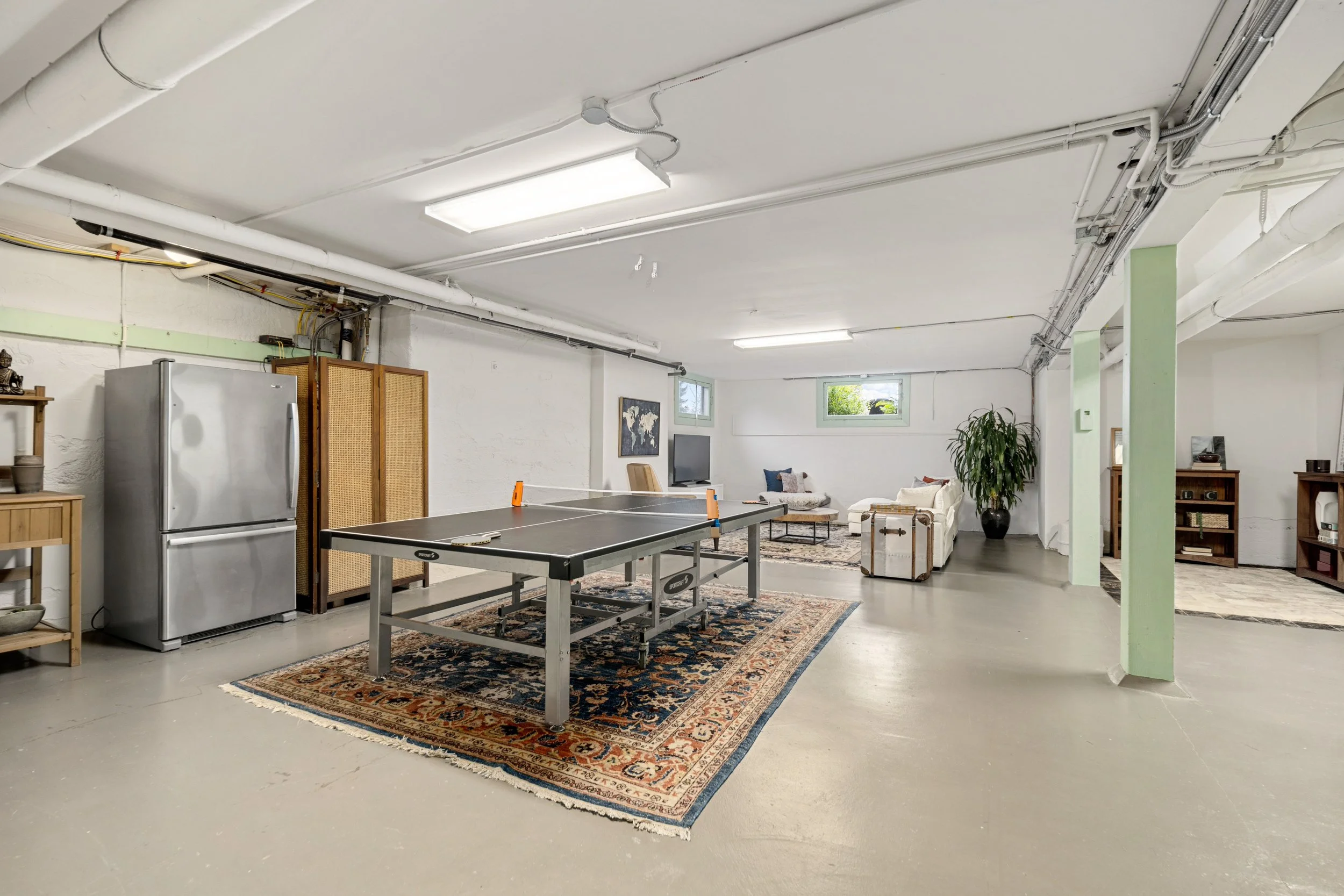 Underground basement with ping pong table, sofa, TV, and storage shelves.