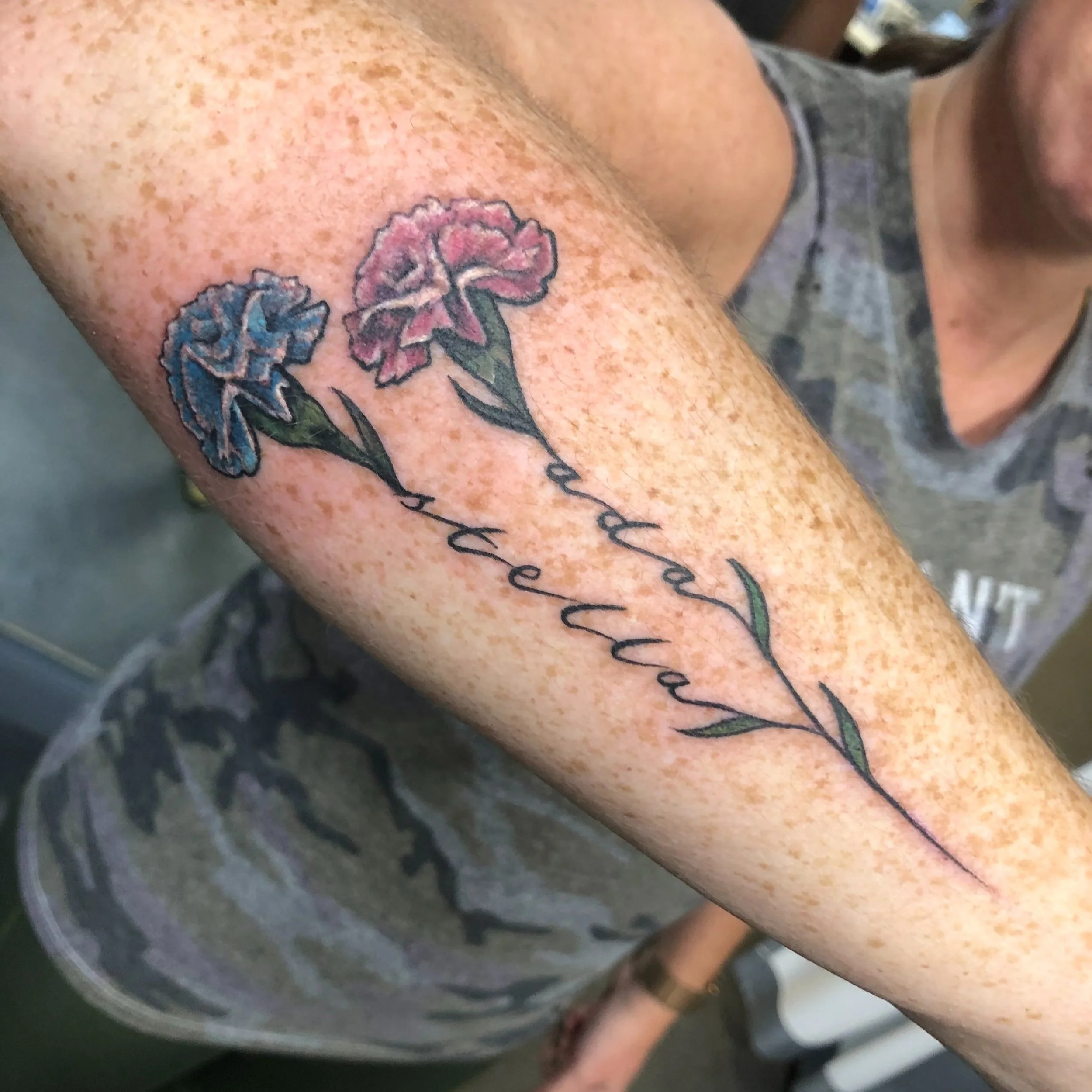 Calligraphed girl names on a tattoo with flowers