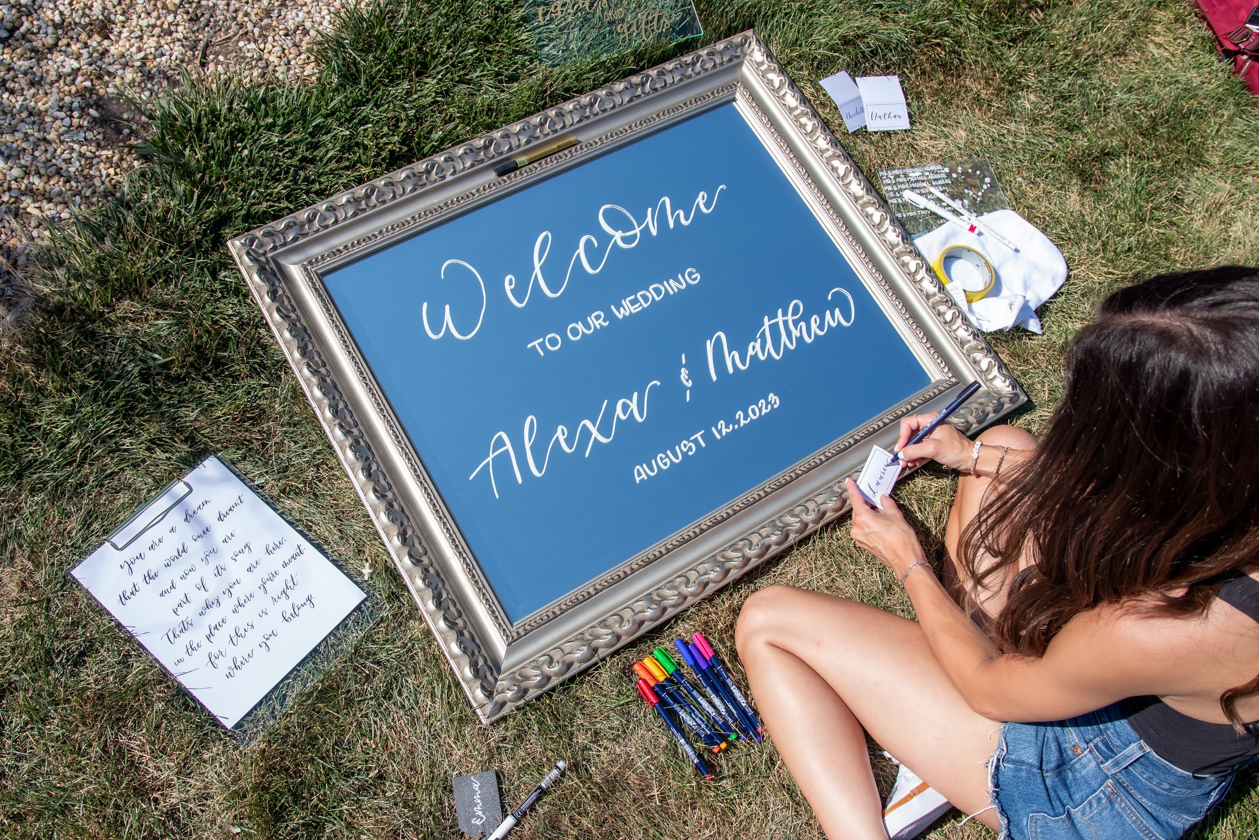 a calligrapher working on a welcome sign for a wedding on an antique style mirror