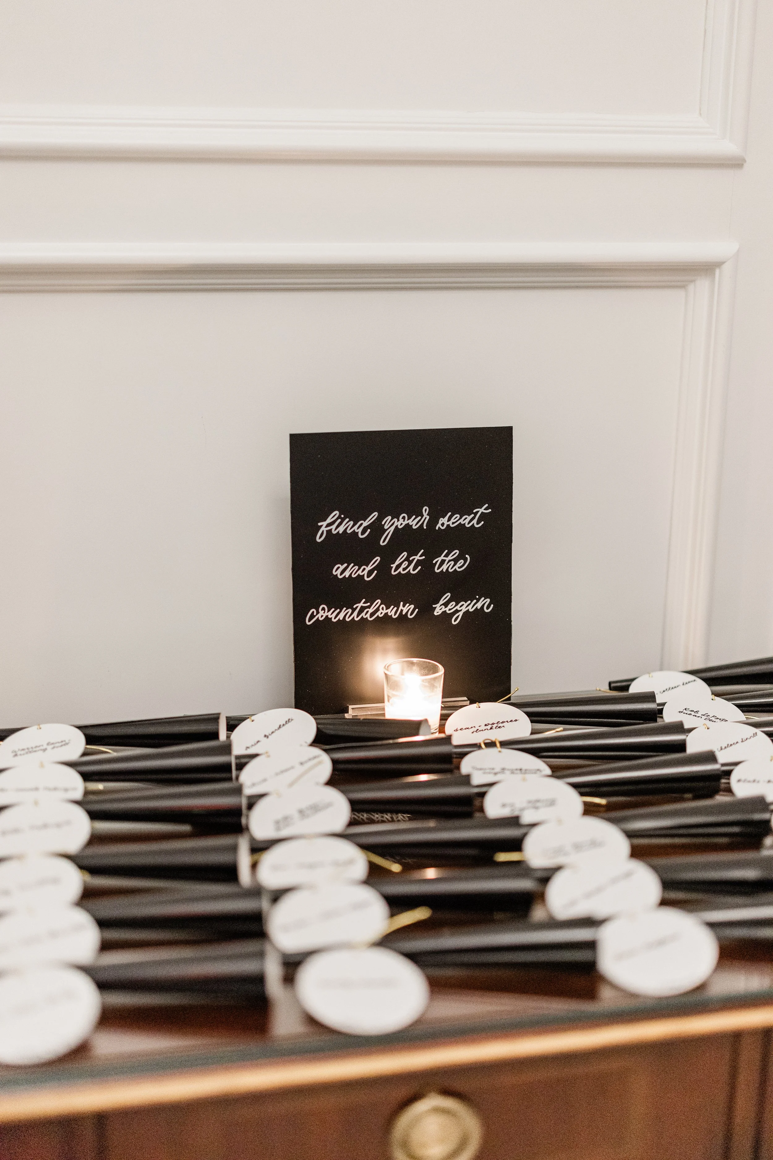 Escort cards handwritten on white acrylic discs with tabletop acrylic sign