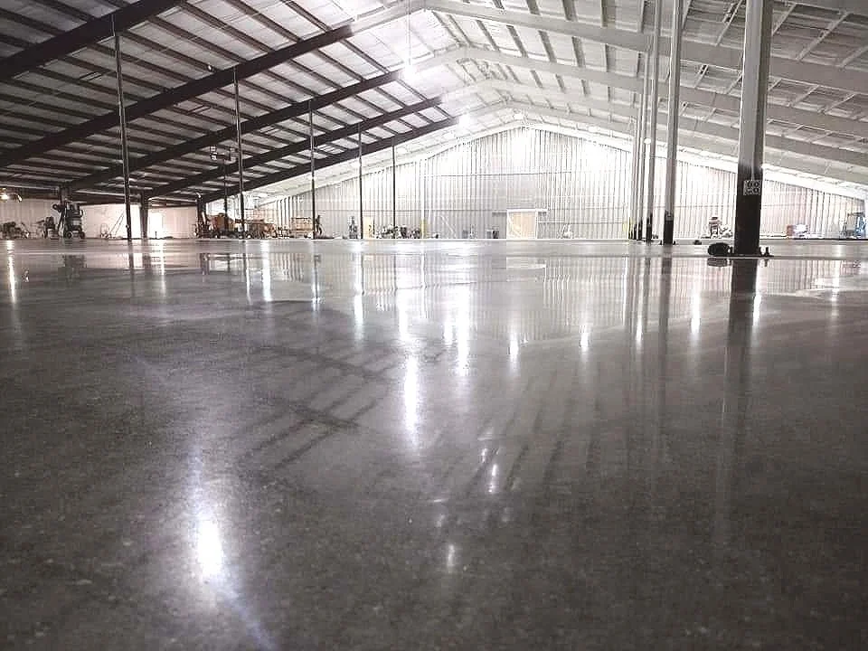 Empty warehouse interior with polished concrete floor and metal structure beams.