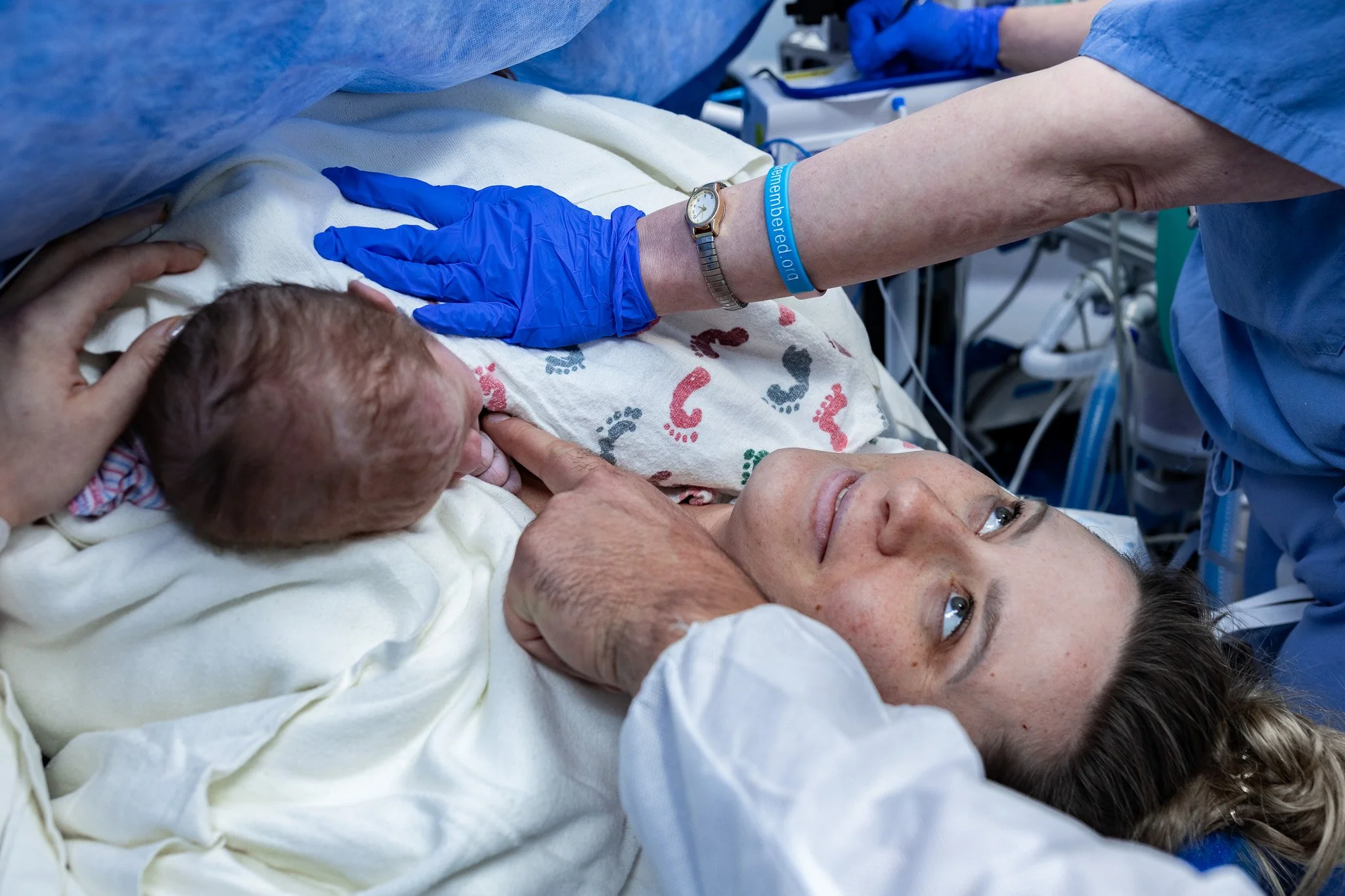 A mother smiles up at her partner after delivering her baby via c-section