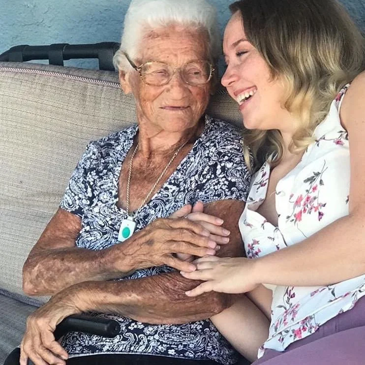 A grandmother and granddaughter are laughing while holding onto each other, hands overlapped; a true depiction of familial love.