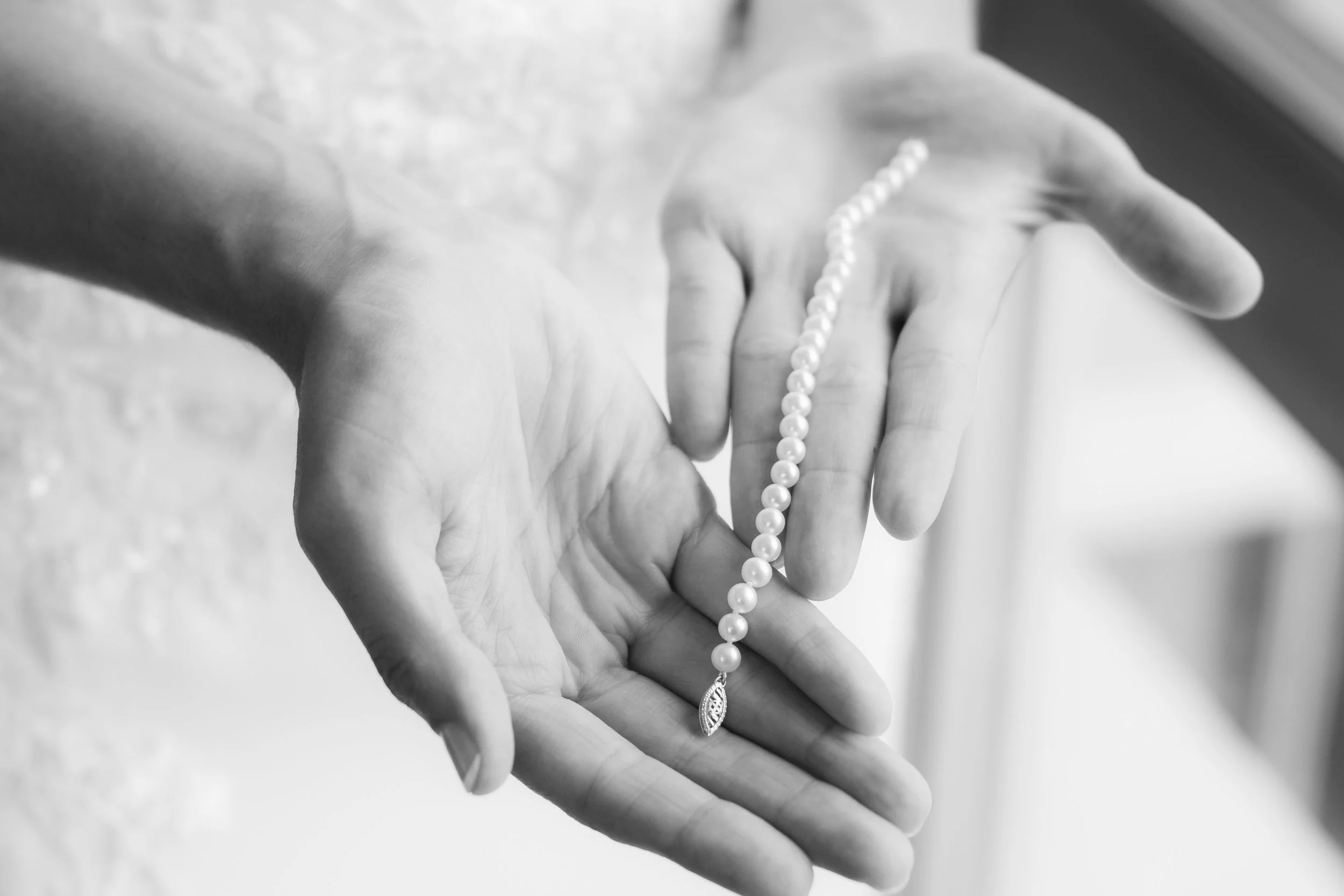 Saratoga Springs New York Wedding Hands holding a pearl necklace in black and white.