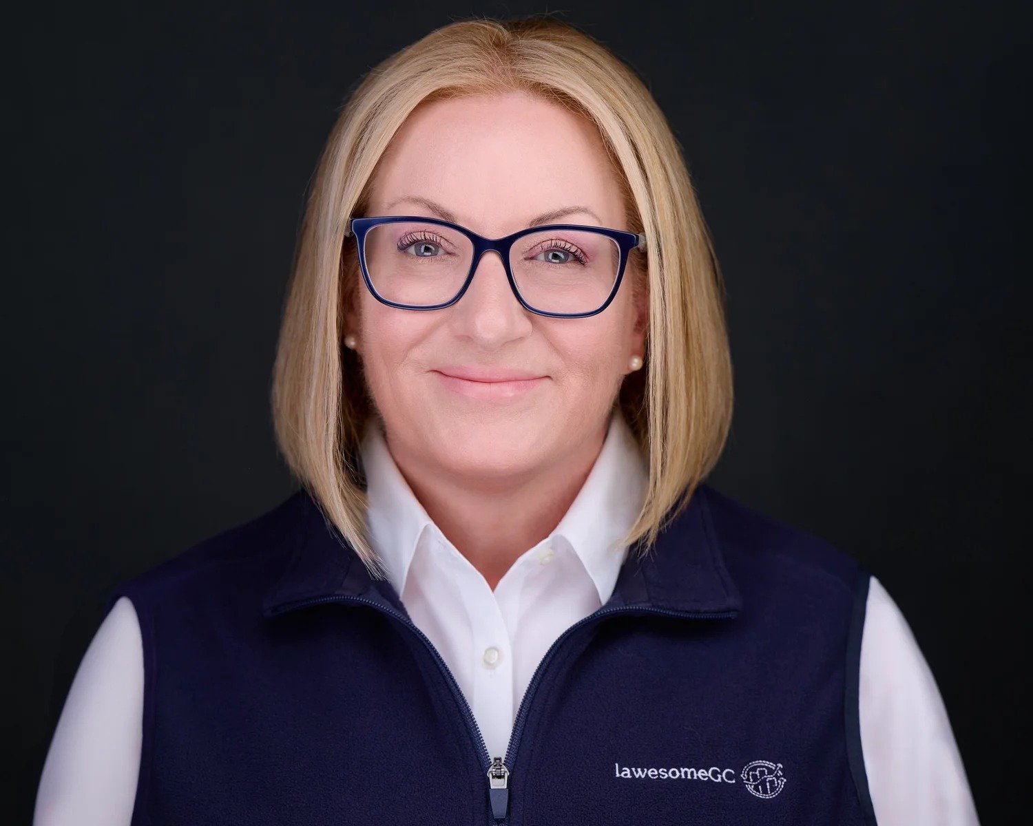 Attorney headshot of a woman in a navy vest and blue glasses, photographed in the Irvine studio