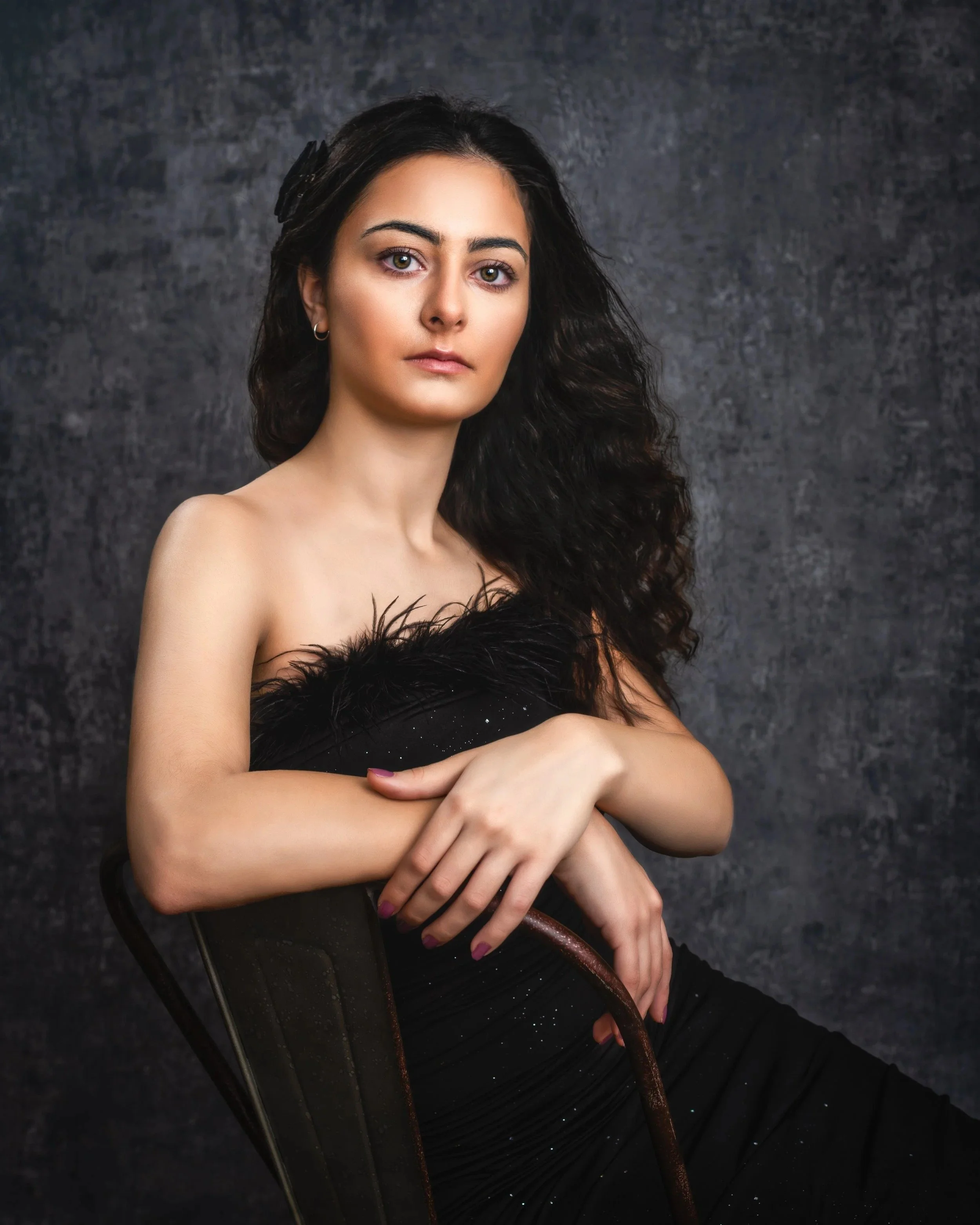 Studio portrait of a woman with long dark curls in a black gown.