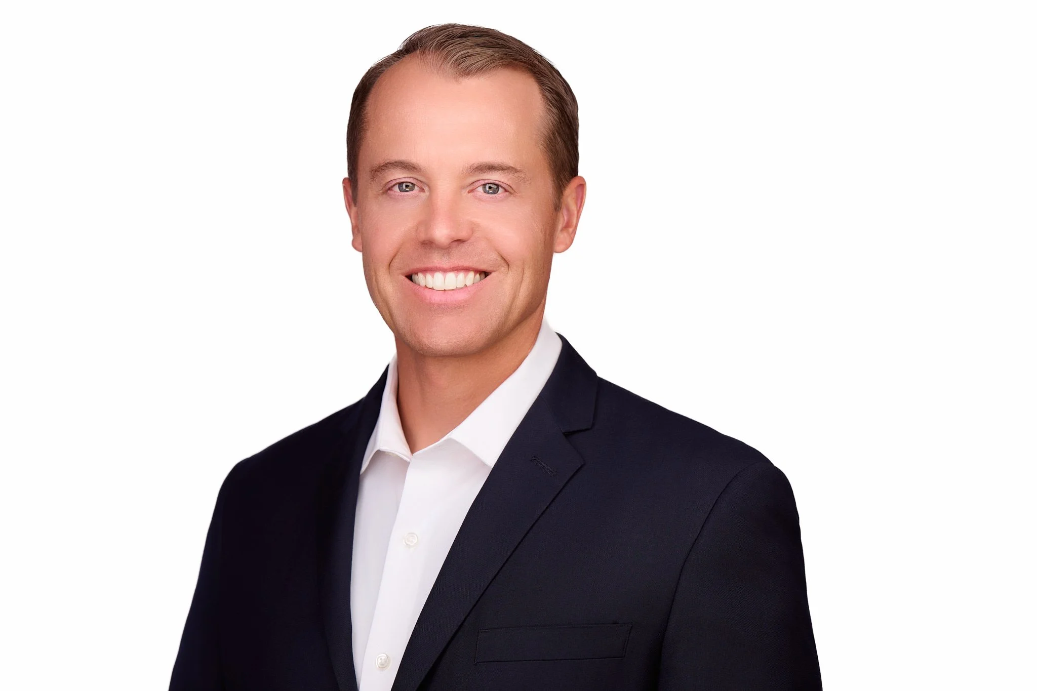 Business headshot of a man in a dark suit and white shirt, photographed on a white background.
