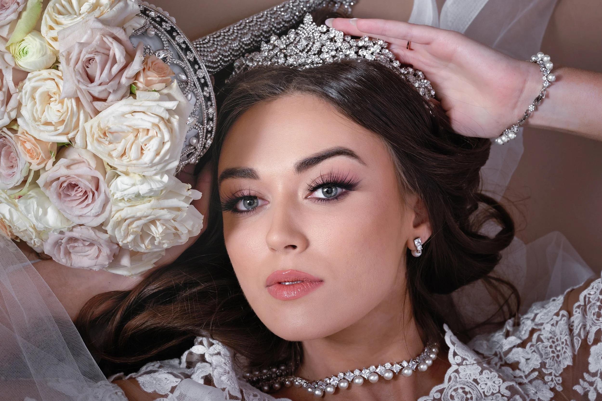 Portrait of a woman in a jeweled tiara lying among roses