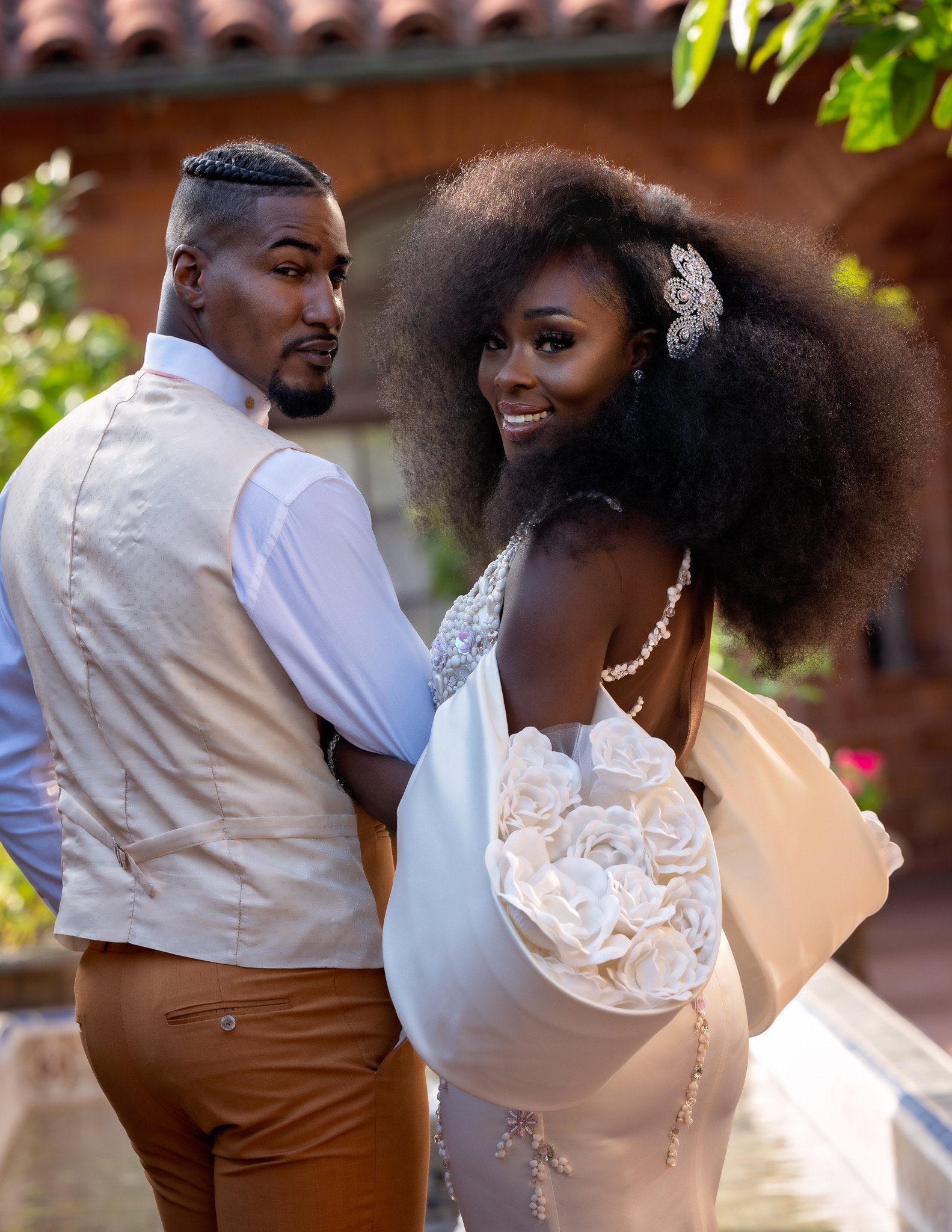 Bride and groom outdoors looking back over their shoulders, from a branding shoot for a bridal gown designer