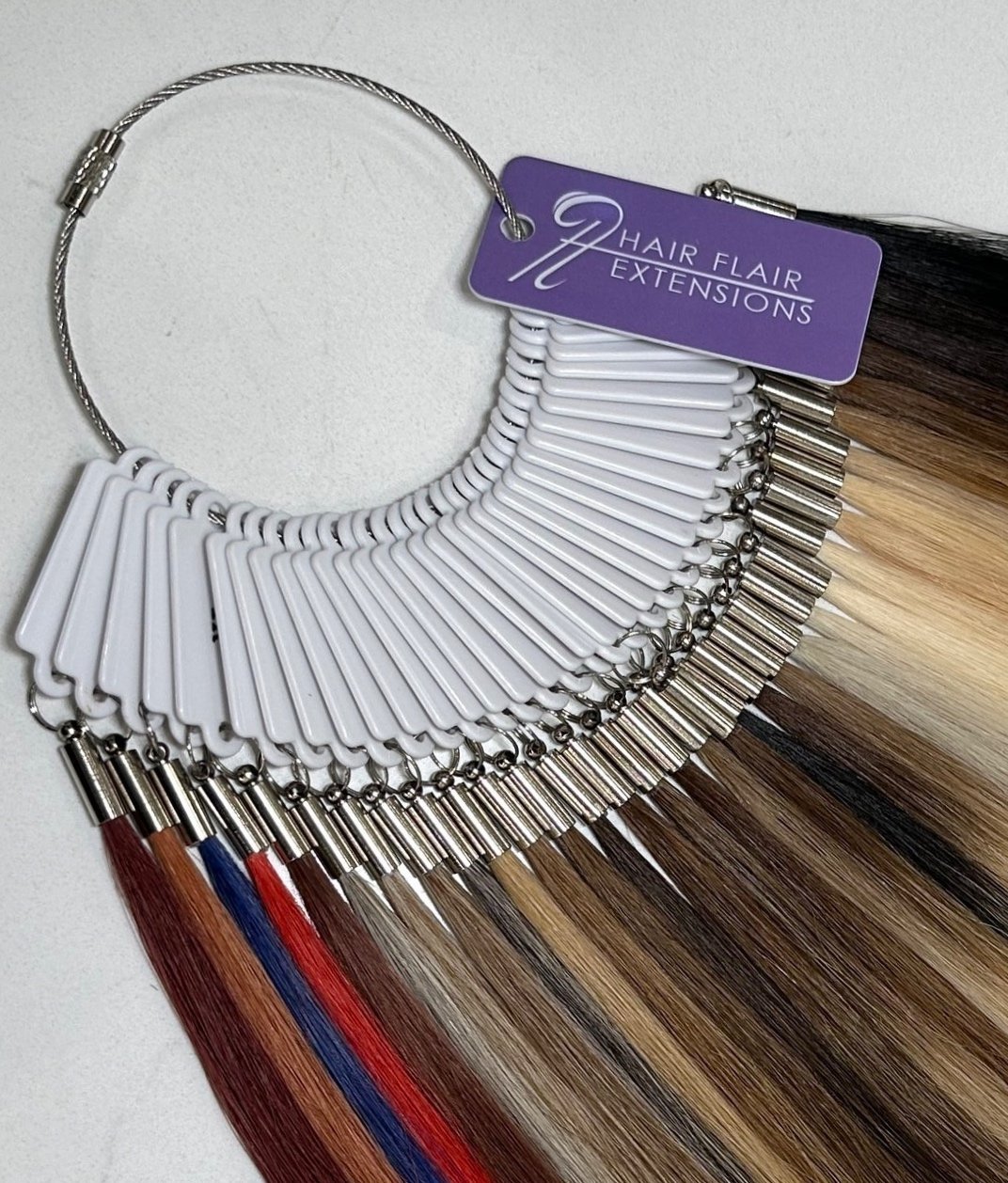 A color palette of hair color samples attached to a necklace-like holder with a tag that reads 'Hair Flair Extensions'.