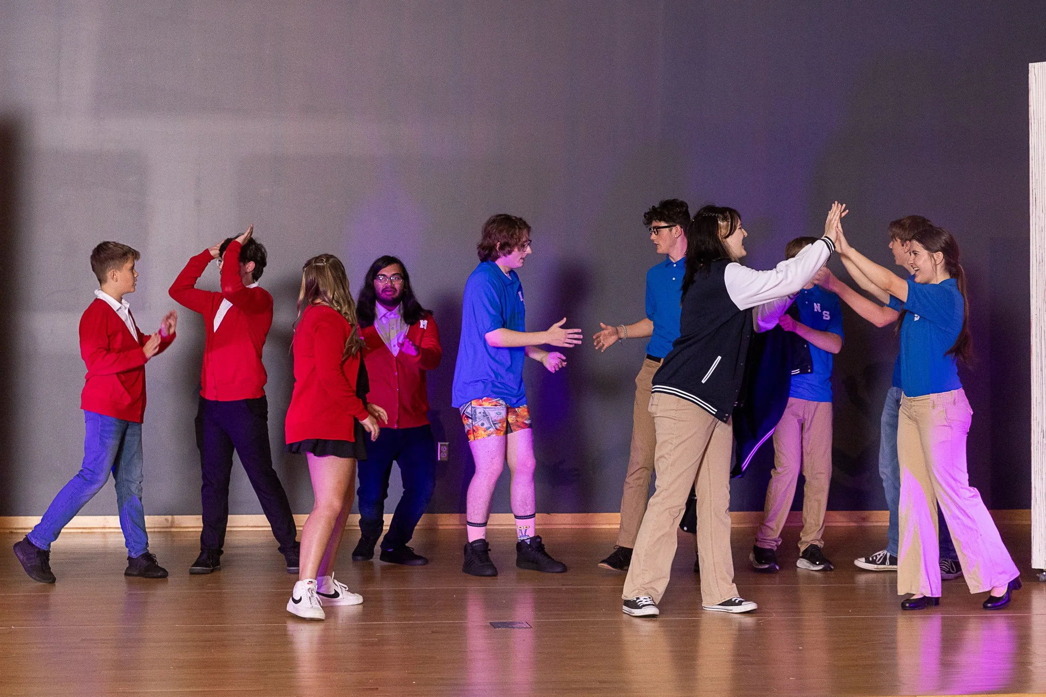 A group of actors high five each other on stage