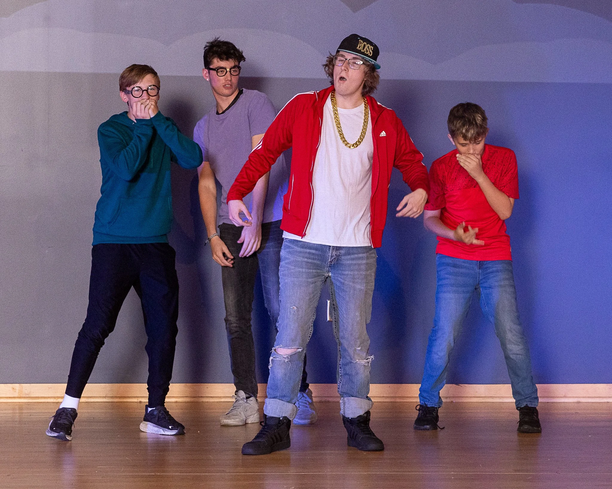 A boy stands in the center of three other boys as they all dance