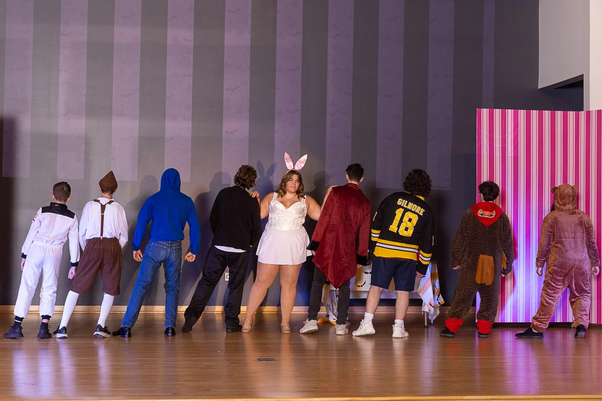 A girl in a bunny costume dances with a group of eight boys