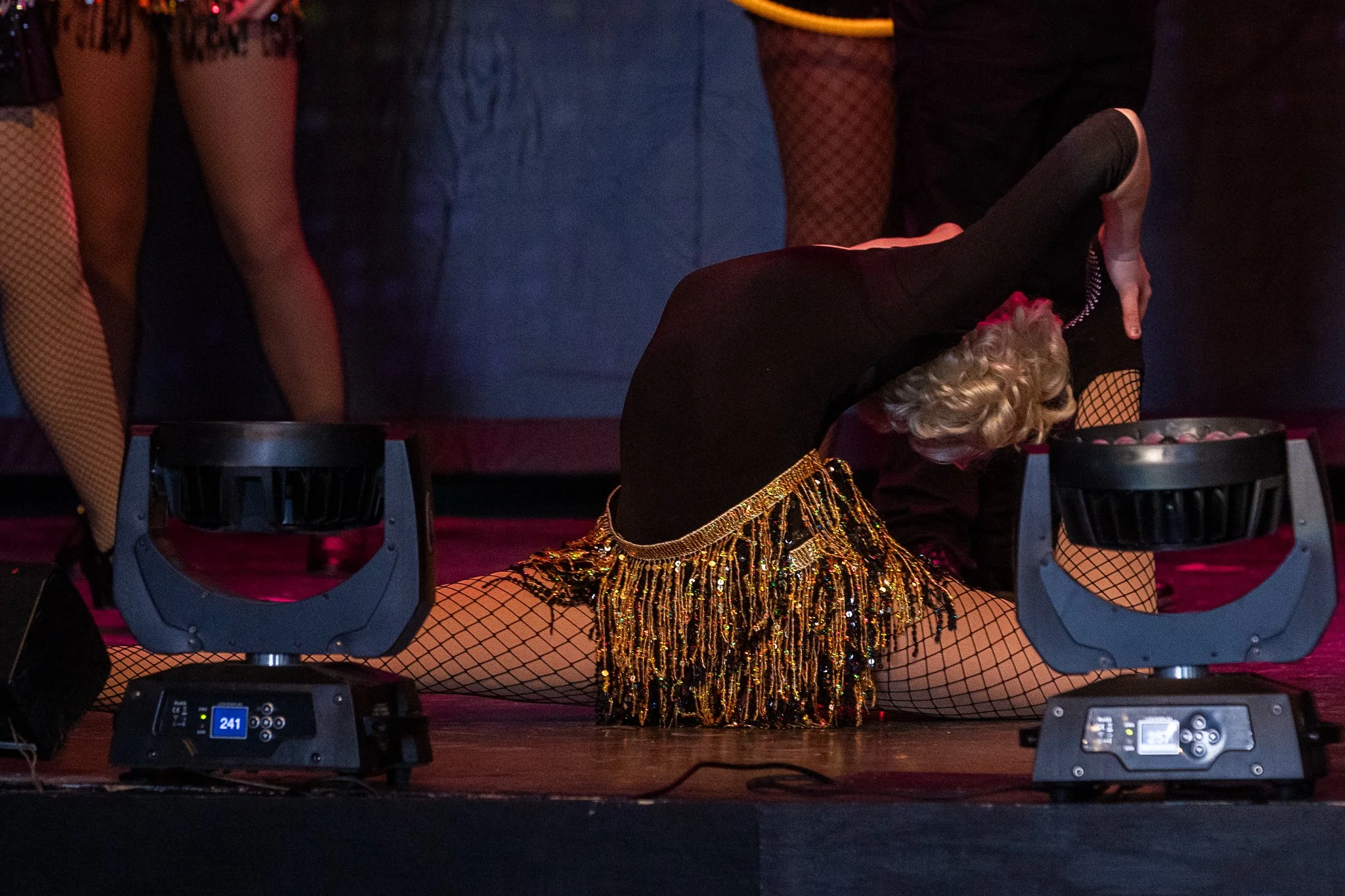 An actor in the splits touches her back leg to her head