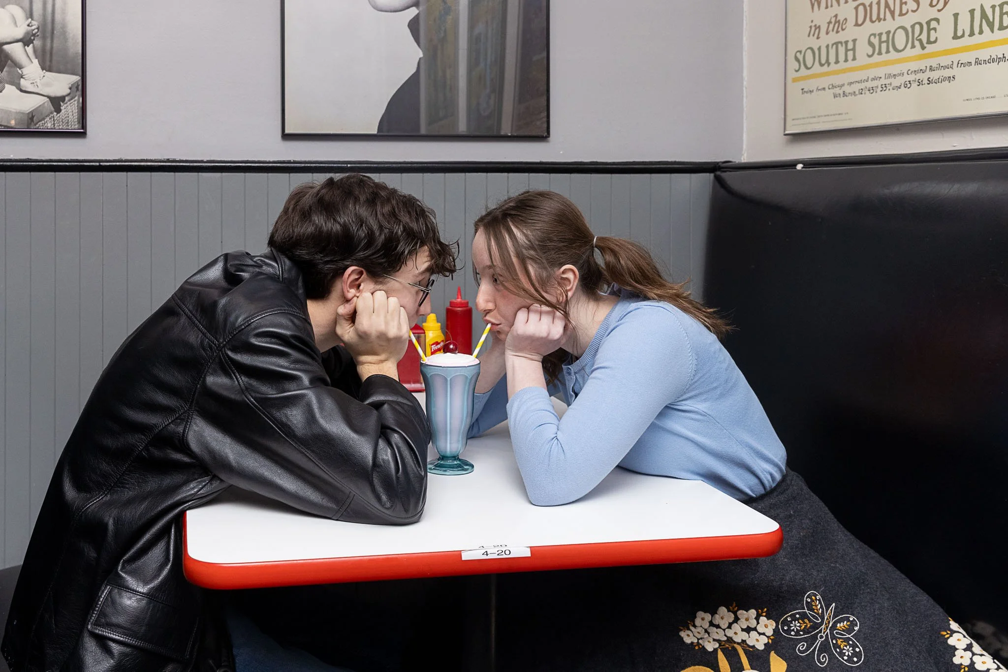 Two actors share a milkshake and gaze at each other