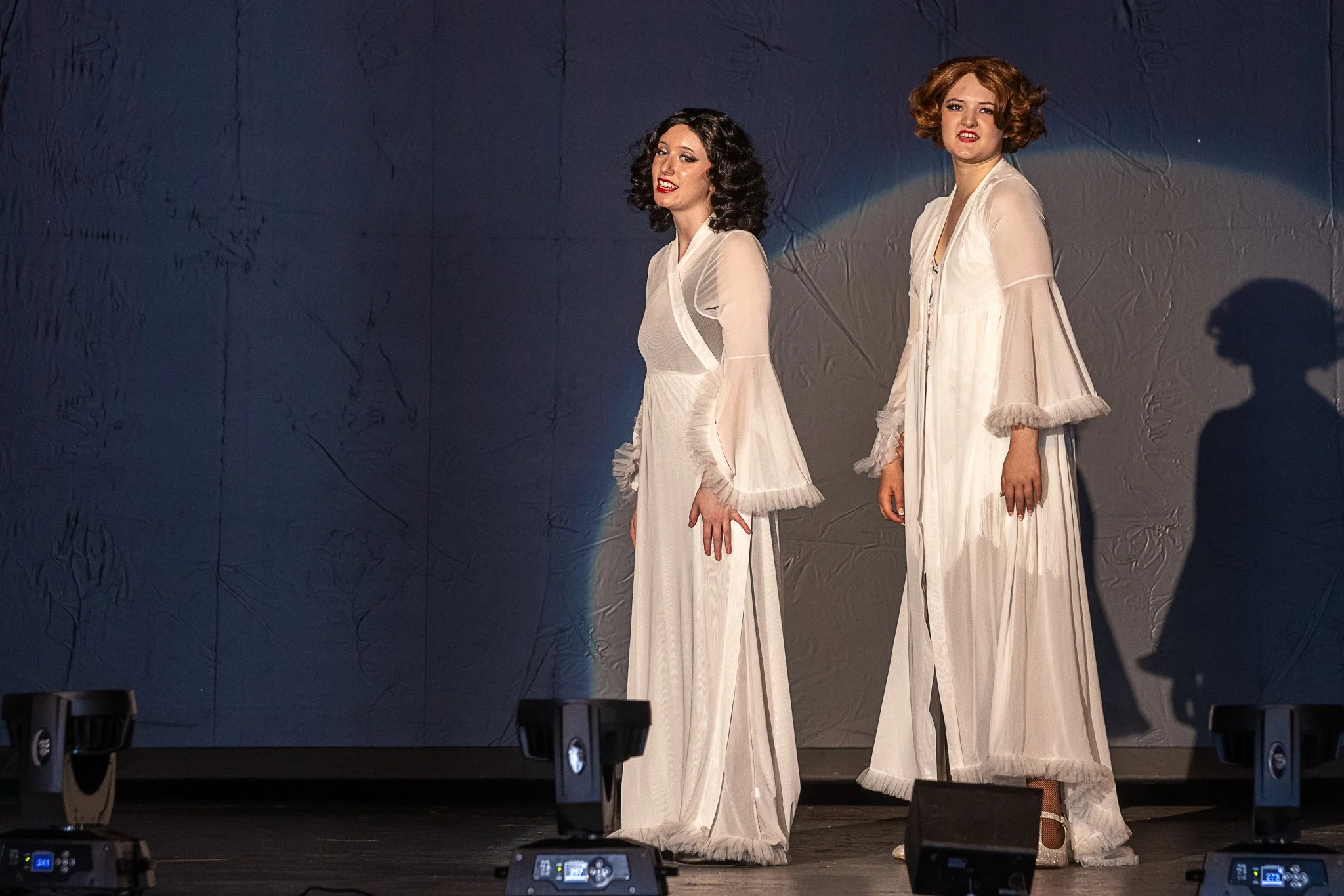 Two actors in white robes walk across the stage