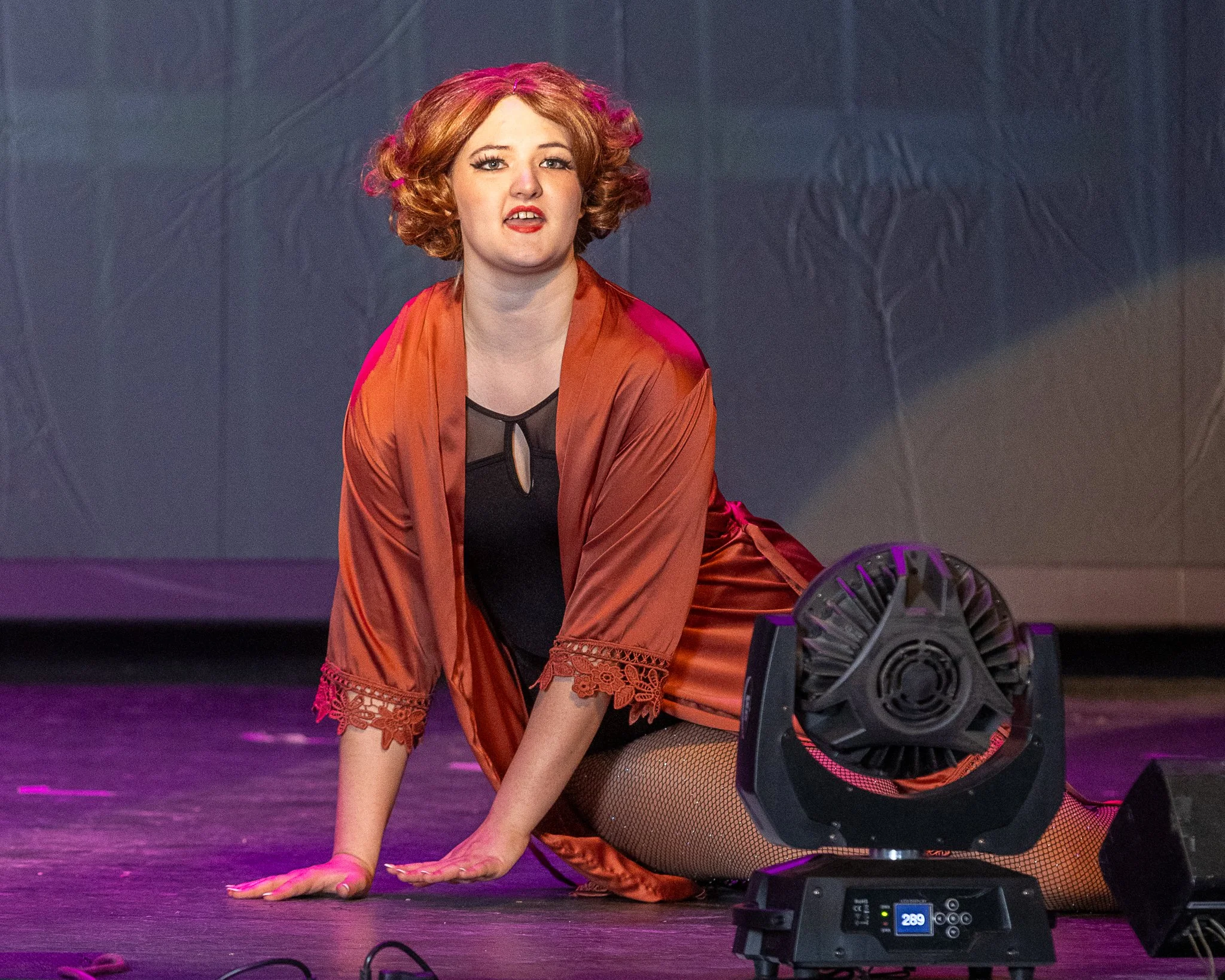 An actor sits on the stage and sings
