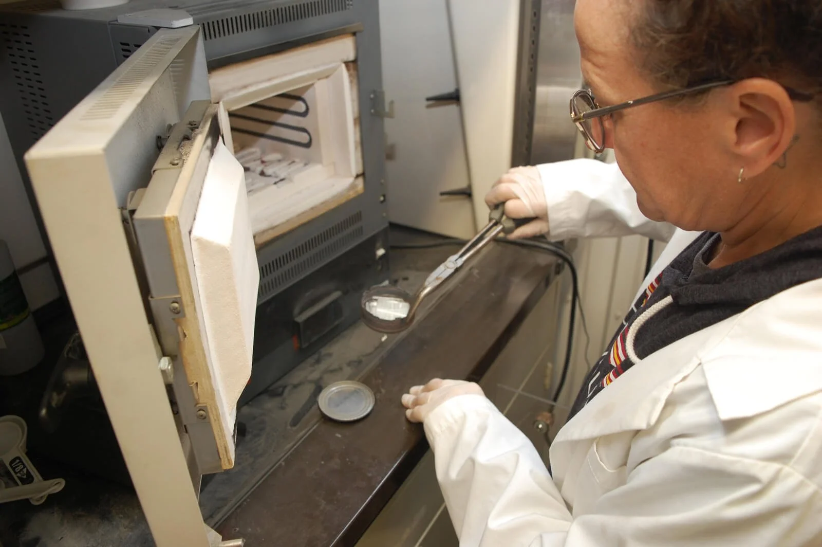 Omega female employee wearing a white lab coat is pulling out a sample a piece from testing equipment for UV CIPP Liner manufacturing quality control