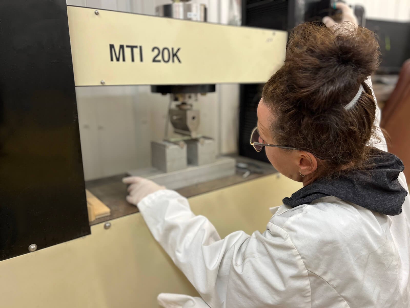 Omega female employee wearing a white lab coat is checking a piece of testing equipment for UV CIPP Liner manufacturing quality control