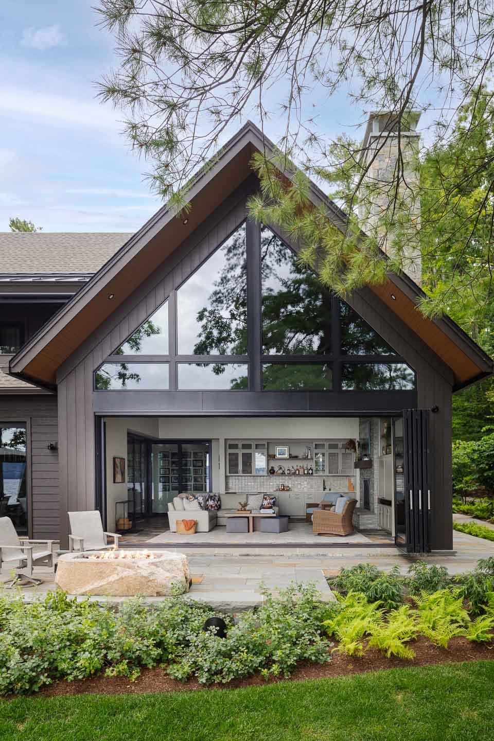 Home with panoramic view of Lake Winnipesaukee with dark brown exterior and floor-to-ceiling window. | Lindsay Lawrence Interiors