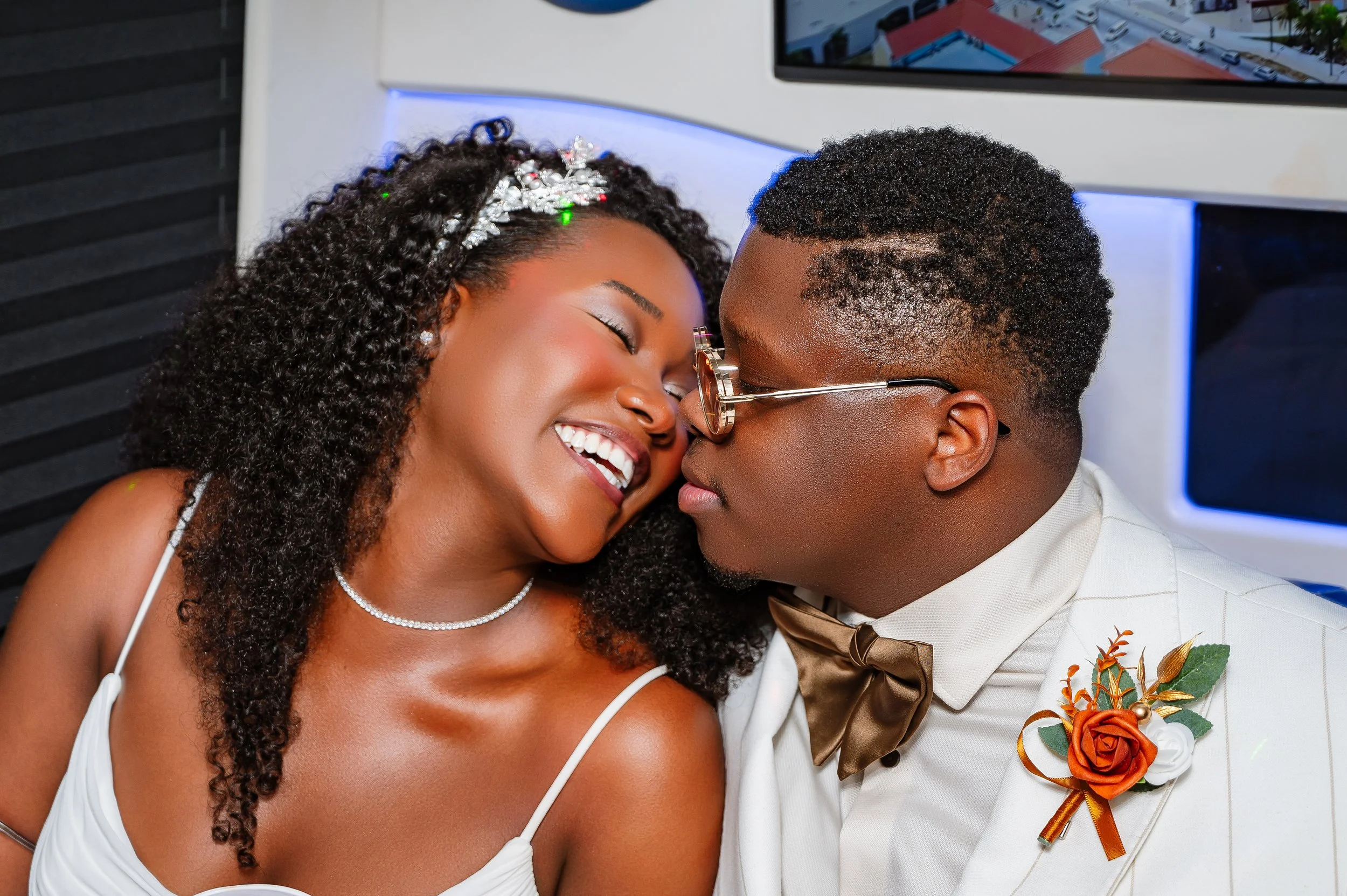 A bride and groom sharing a close, intimate moment at their wedding, smiling and touching foreheads, dressed in wedding attire with festive details.