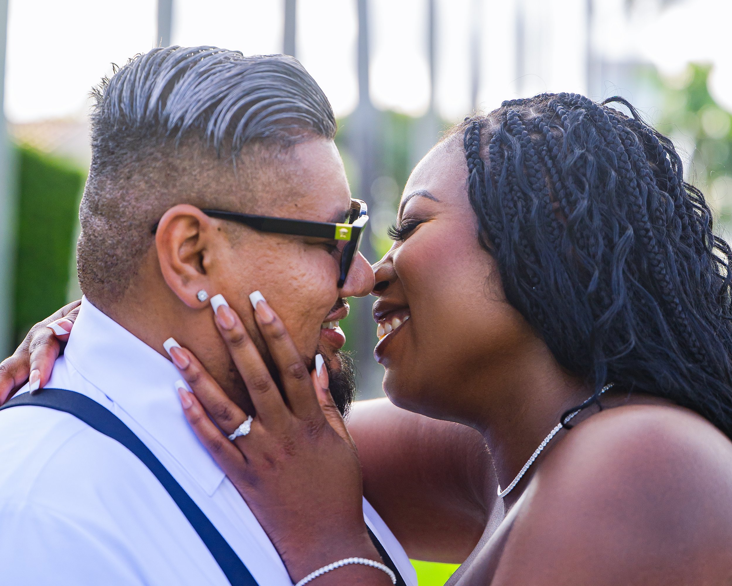 A couple is smiling and about to kiss, with the woman's hand on the man's face and both looking at each other