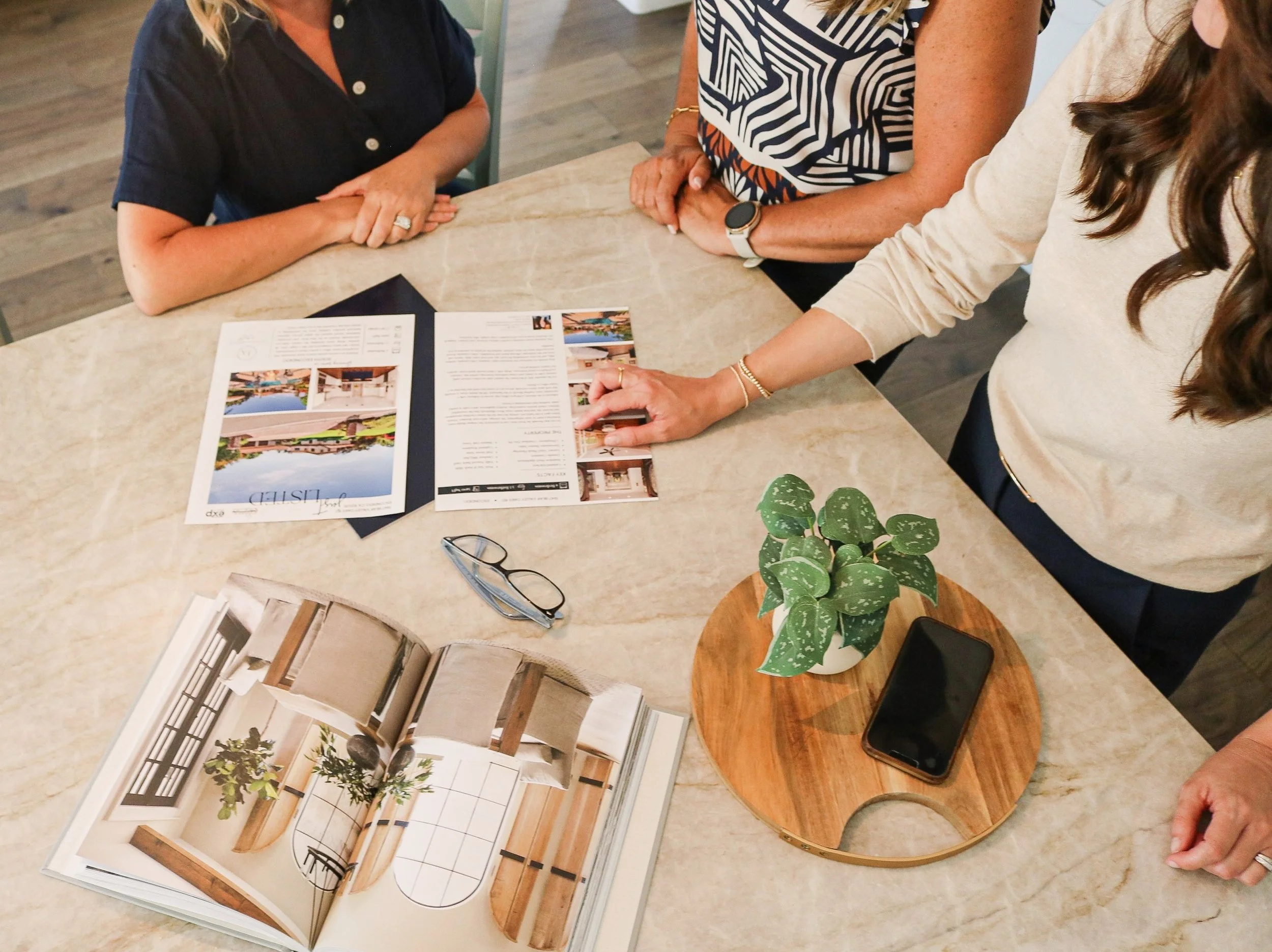 Jessica Adams and the Legacy Homes and Estates team reviewing home listing materials at a kitchen island in North County San Diego