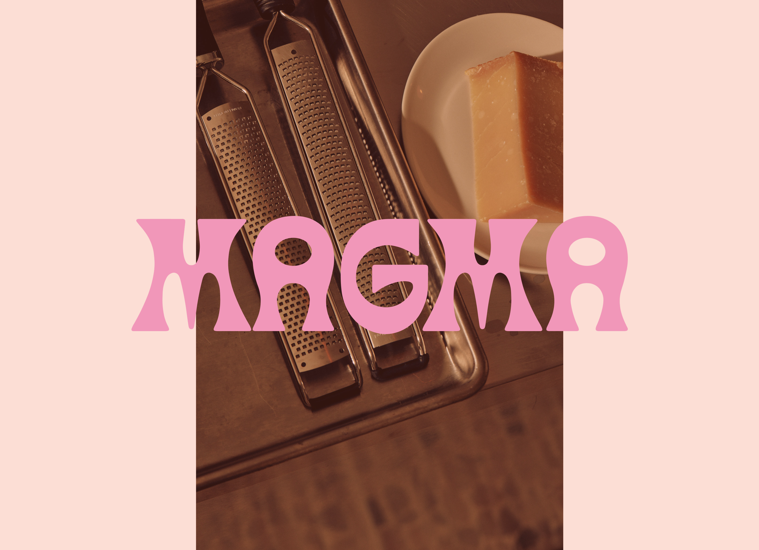 Two stainless steel graters lay on a metal surface next to a white bowl containing a large block of hard cheese, with pink text overlay that reads "Magma"
